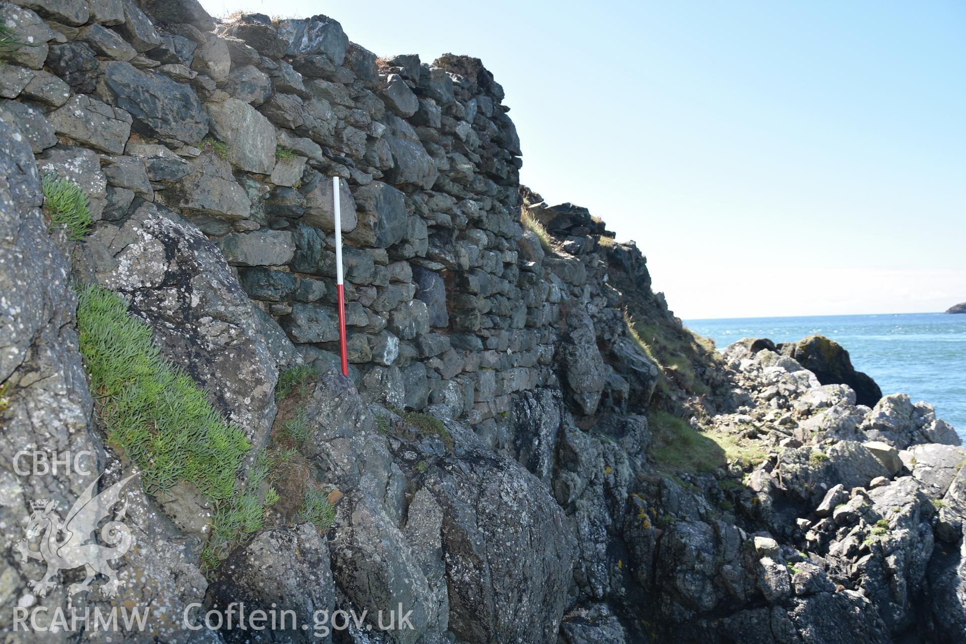 Penmaenmelyn copper mine. View of western revetment wall from north. 1m scale. Investigator?s photographic survey for the CHERISH Project. ? Crown: CHERISH PROJECT 2019. Produced with EU funds through the Ireland Wales Co-operation Programme 2014-2020. All material made freely available through the Open Government Licence.