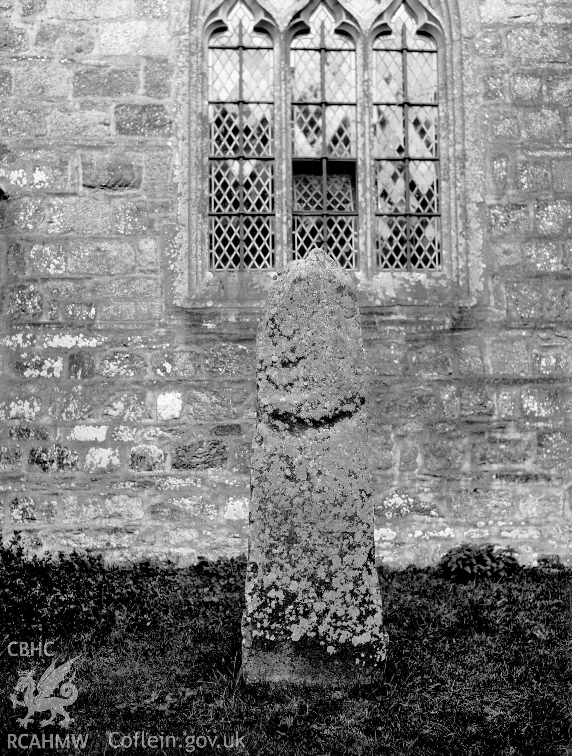 Digital copy of a nitrate negative showing exterior view of pillar stone in the churchyard of St Brynach's Church, Nevern. From the National Building Record Postcard Collection.