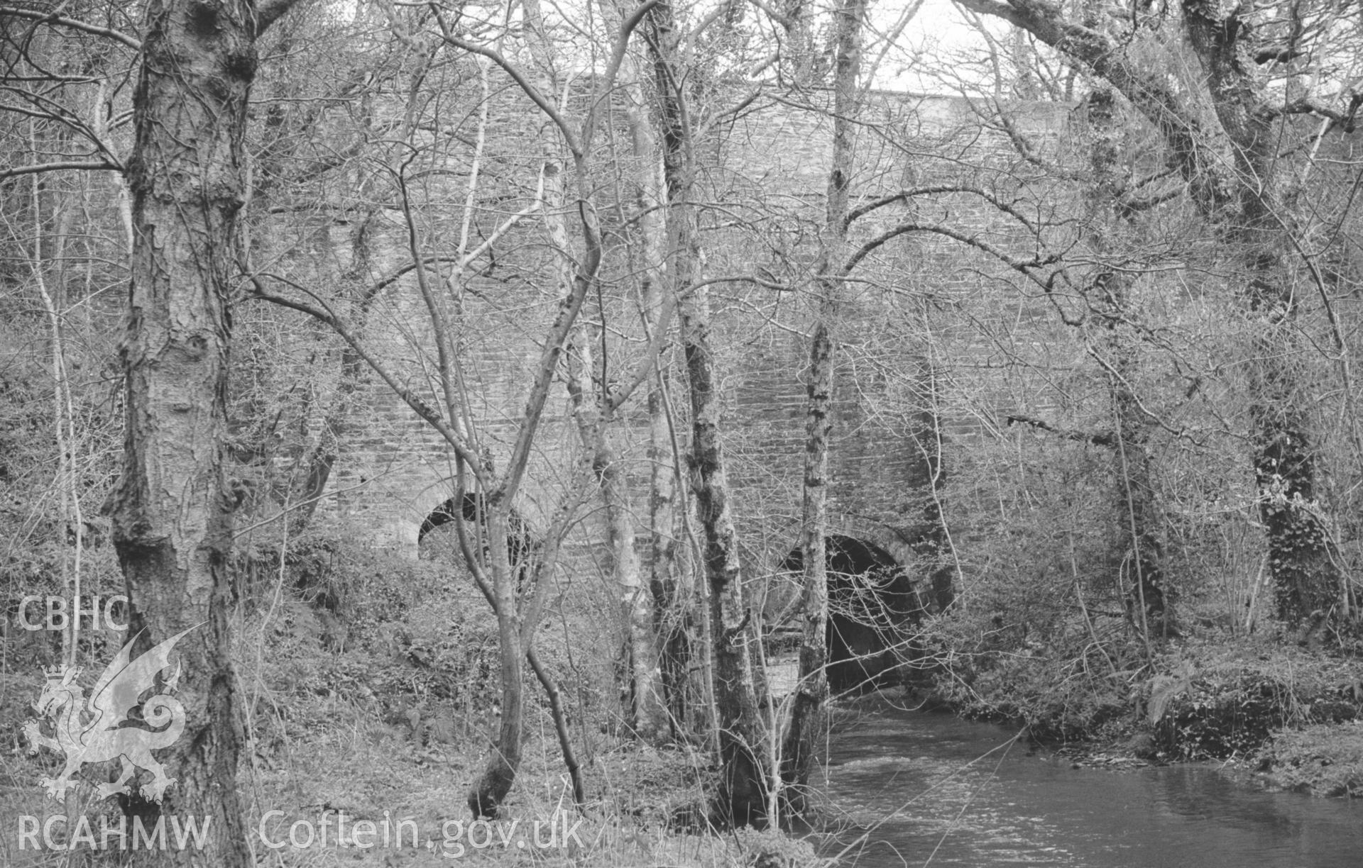 Digital copy of black and white negative showing view looking upstream to the bridge over Nant Gwylan on the Henllan-Llandyfriog road at Felin Cwrrws. Photographed by Arthur O. Chater in April 1966 from Grid Reference SN 354 412, looking east north east.
