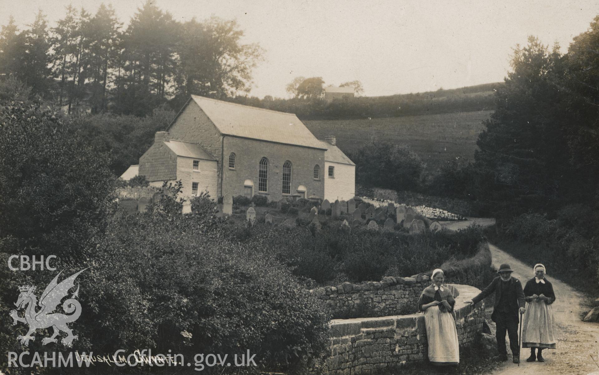 Digital copy of monochrome postcard showing exterior view and graveyard of Jerwsalem Welsh Independent chapel, Llangadog, with two women and a man in the foreground. Loaned for copying by Thomas Lloyd.