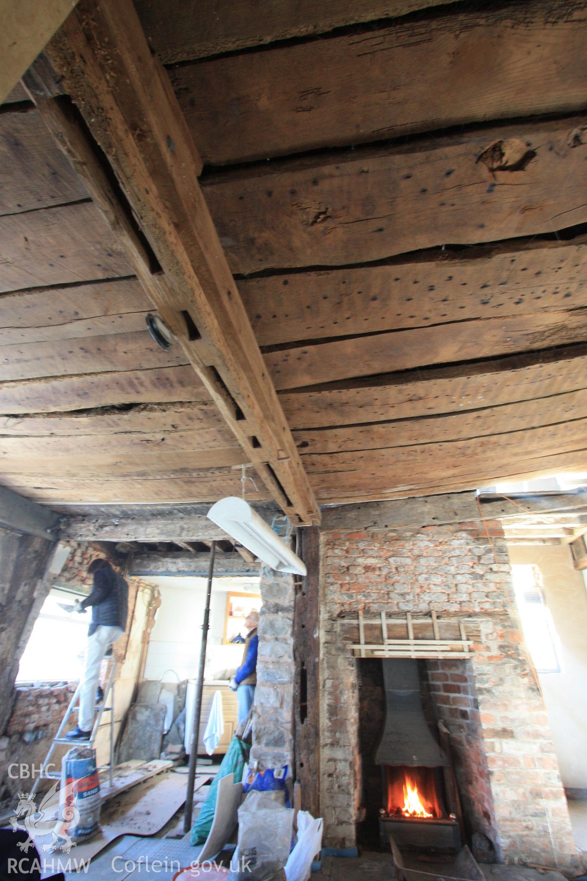 Colour photograph showing transverse beam of cross-wing, detail of mortices and red brick fireplace at Porth-y-Dwr, 67 Clwyd Street, Ruthin. Photographed during survey conducted by Geoff Ward on 10th June 2013.