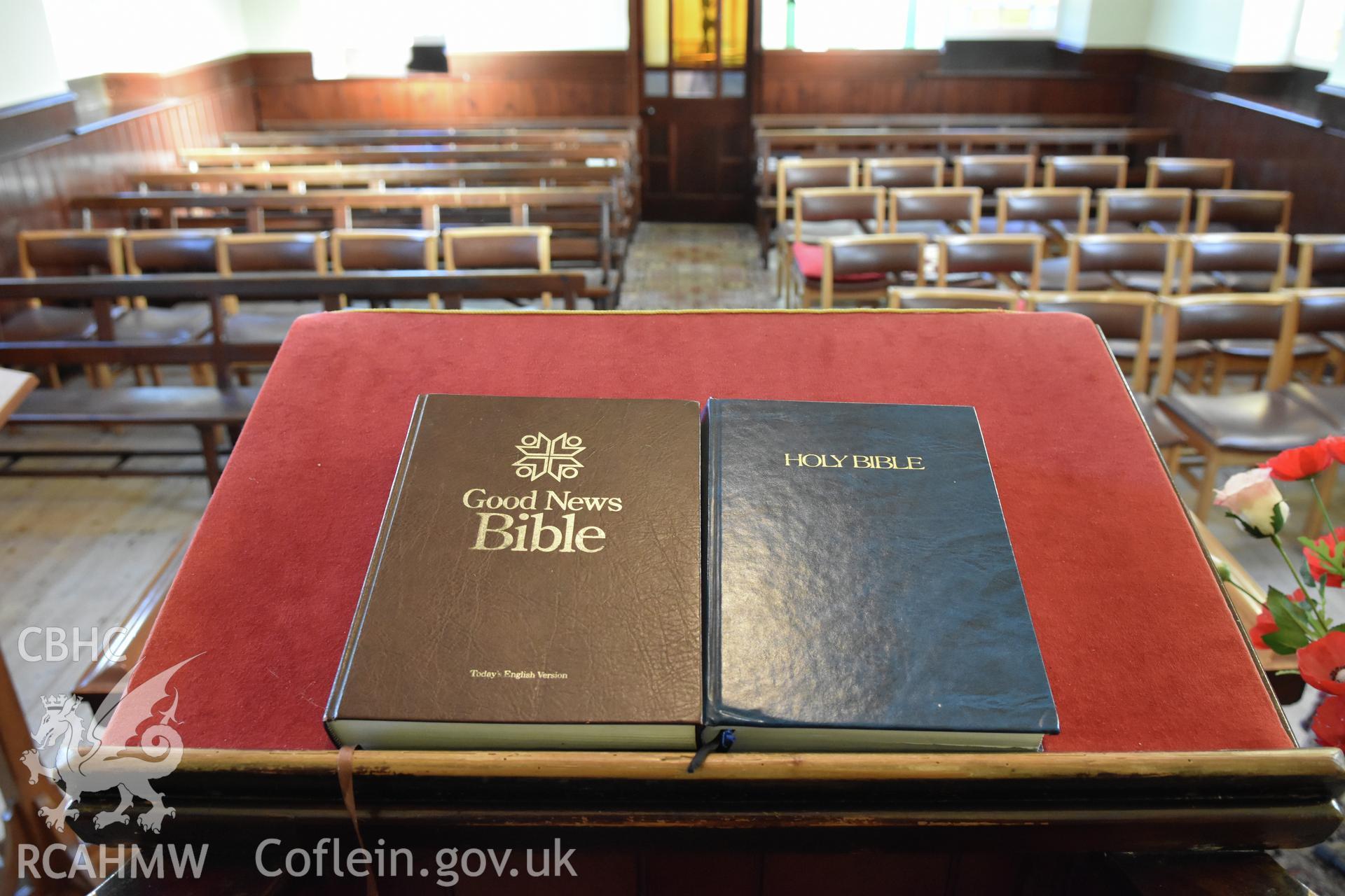 View of two bibles on the wooden pulpit at Hyssington Primitive Methodist Chapel, Hyssington, Churchstoke, with seating for the congregation beyond. Photographic survey conducted by Sue Fielding on 7th December 2018.