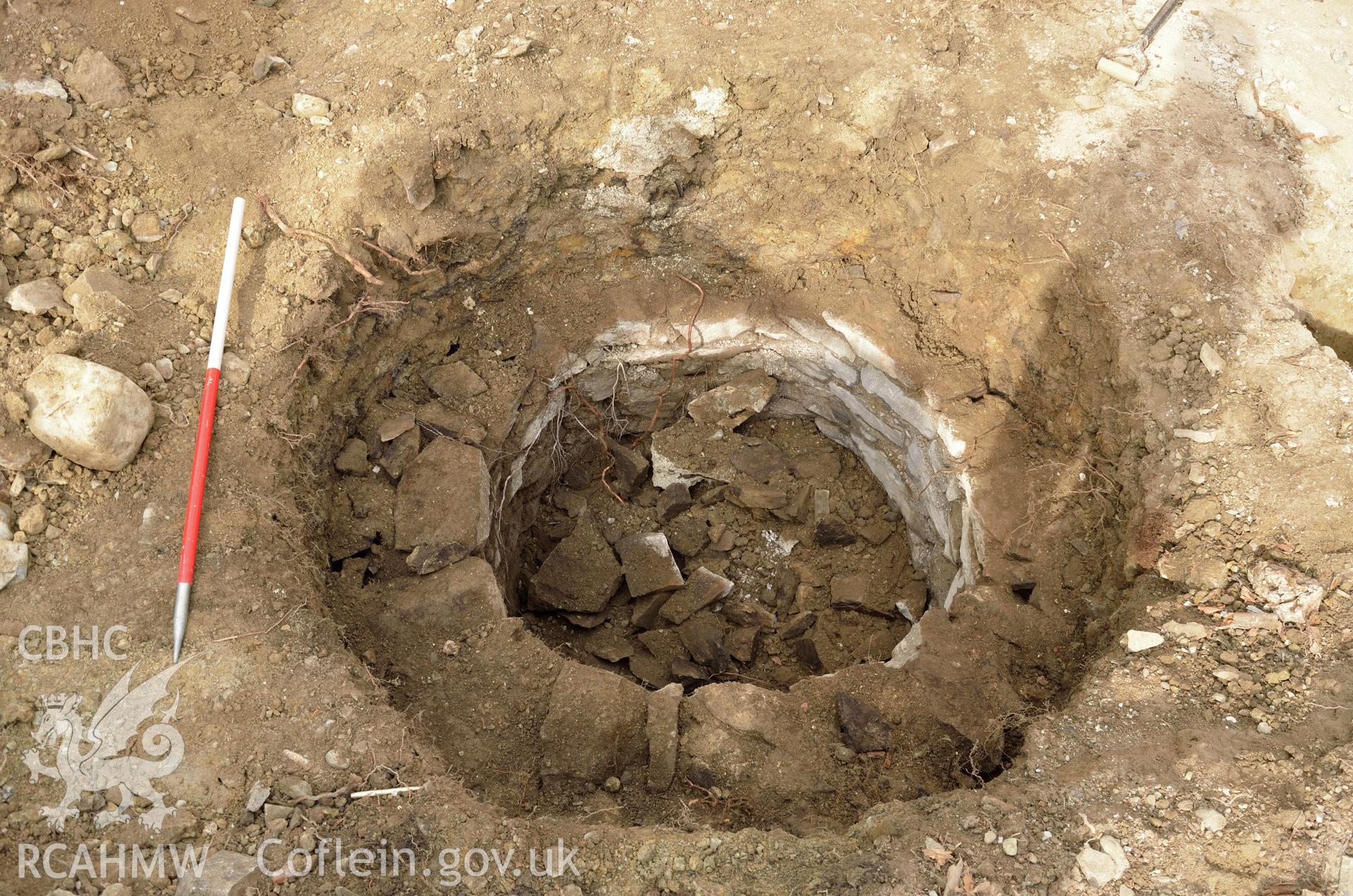 'Cut of well after removal of top 0.5m of stone, viewed from the north east.' Photographed by Gwynedd Archaeological Trust as part of archaeological mitigation report for well at Plas Celynin, Henryd, Conwy, on 6th August 2018. Project no. G2568.