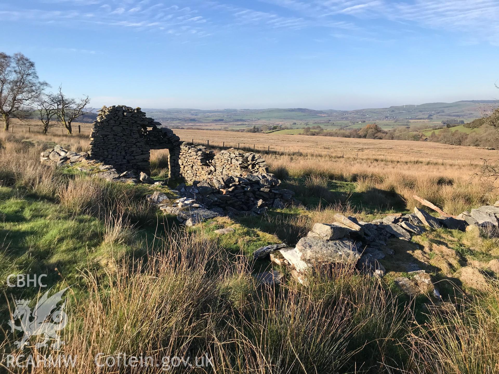 View of the remains of a doorway and stone walls belonging to a cottage west of the ruined Caradog house, which is south west of Bryneithinog farm, Ystrad Fflur. Colour photograph taken by Paul R. Davis on 18th November 2018.