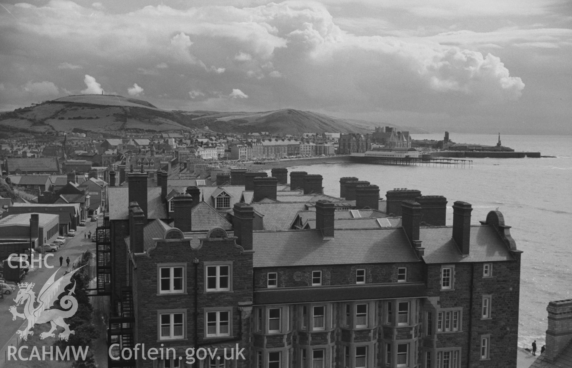 Digital copy of a black and white negative showing views over Aberystwyth from the lower slopes of Constitution Hill with Alexandra Hall in the foreground. Photographed by Arthur O. Chater on 15th August 1967 looking south from Grid Reference SN 583 826.