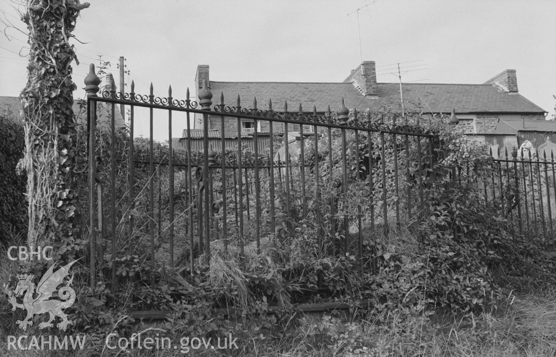 Digital copy of black & white negative showing wrought iron railings around graves in old churchyard at Holy Cross church, Llechryd, south east of Cardigan. Photographed by Arthur O. Chater in September 1964 from Grid Reference SN 2184 4372, looking north.