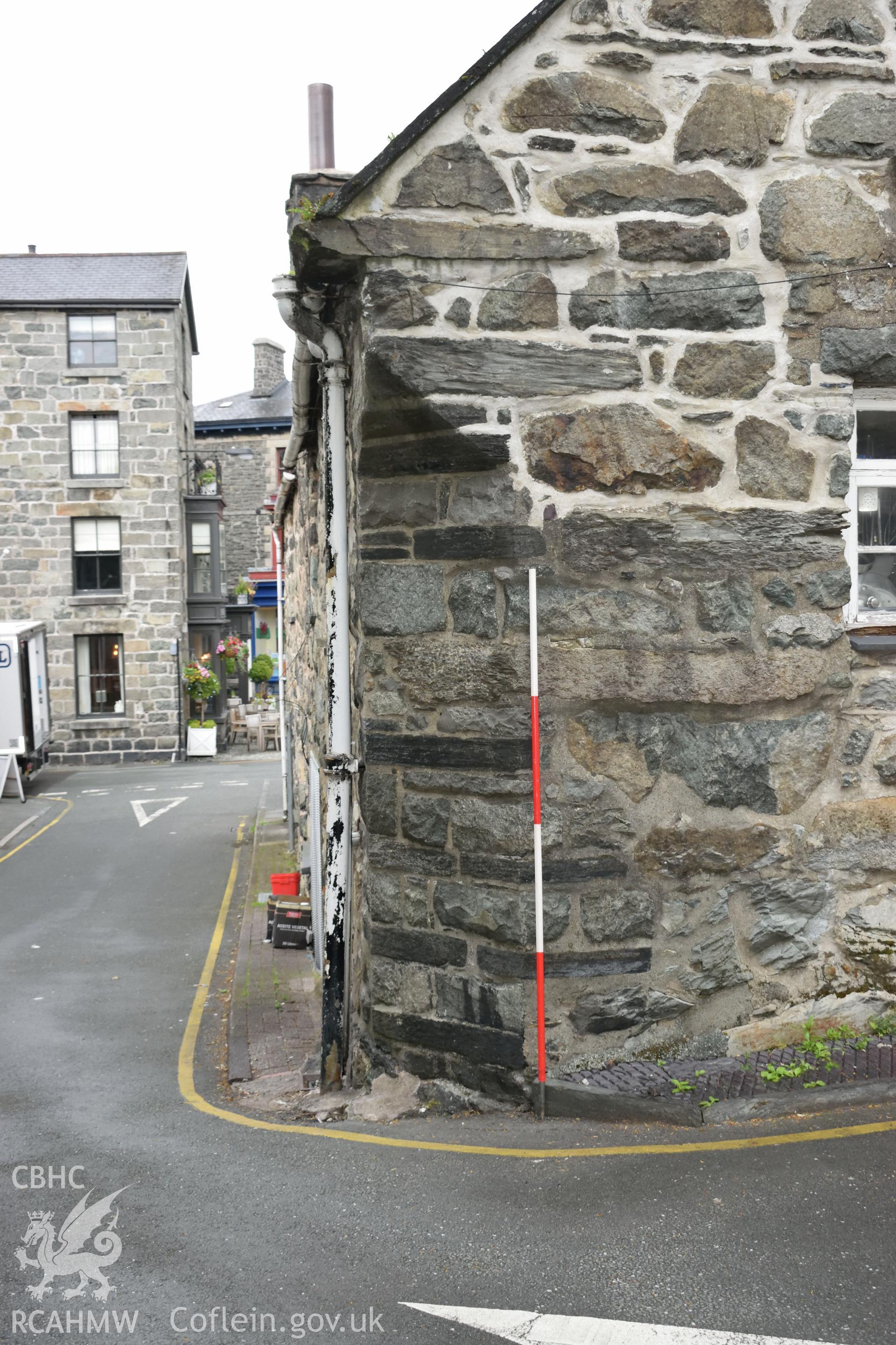 Colour photograph showing view looking east at clipped corner in the north west corner of Y Sospan, Llys Owain, Dolgellau. Photographed by I. P. Brookes of Engineering Archaeological Services, June 2019.
