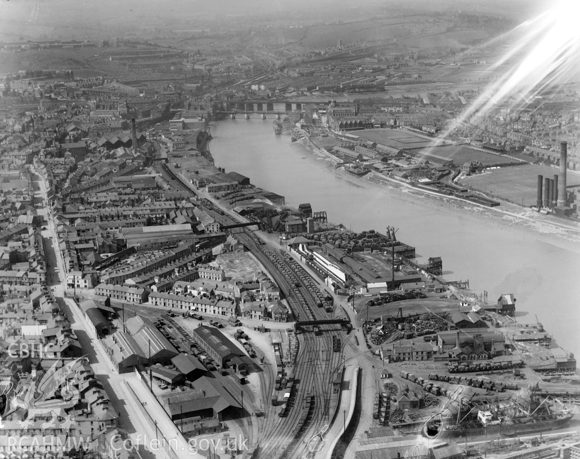 View of Newport showing Rodney Parade, rail and road bridges, and dry dock, oblique aerial view. 5?x4? black and white glass plate negative.