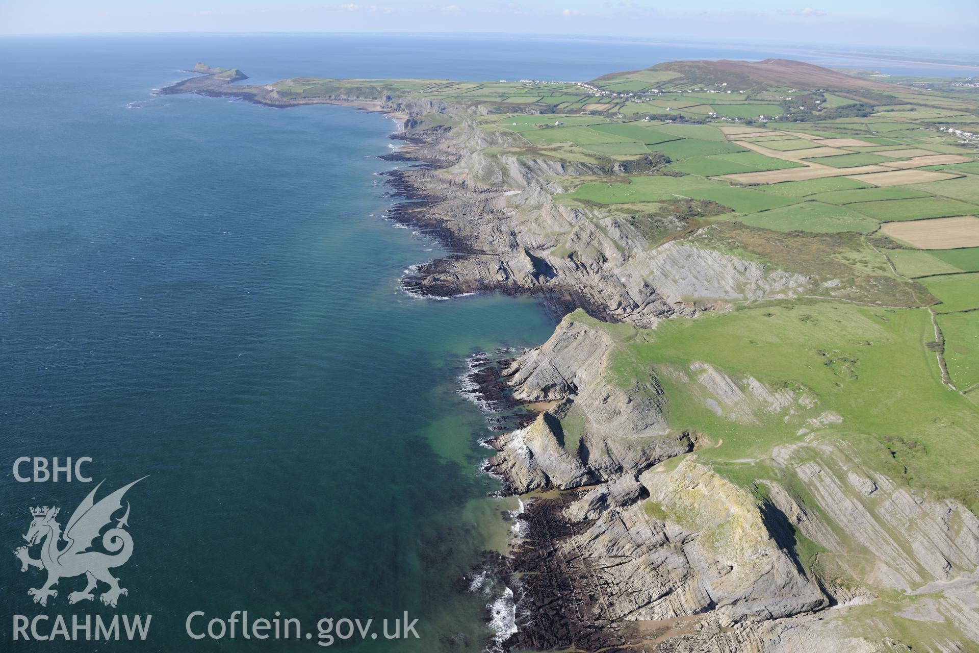 Horse Cliff promontory fort, Yellow Top fort & in the distance, Worm's Head, on south western shore of Gower Peninsula. Oblique aerial photograph taken during Royal Commission?s programme of archaeological aerial reconnaissance by Toby Driver, 30/09/2015.