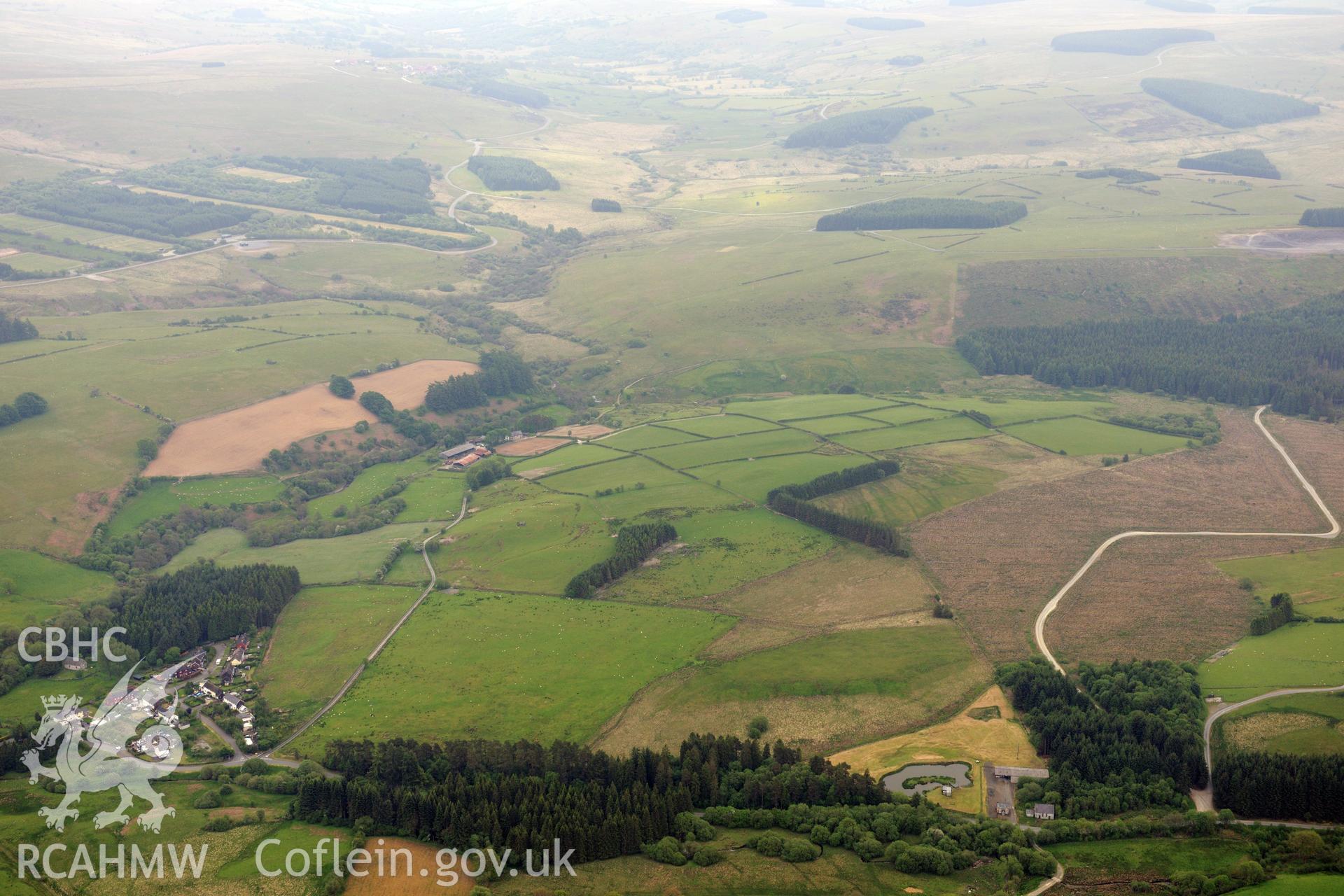 Tirabad village including views of Tirabad enclosure; an enclosure at Gledrydd, near Tirabad and a possible Roman fort at Caerau, Tirabad near Llanwrtyd Wells. Oblique aerial photograph taken during the Royal Commission's programme of archaeological aerial reconnaissance by Toby Driver on 11th June 2015.