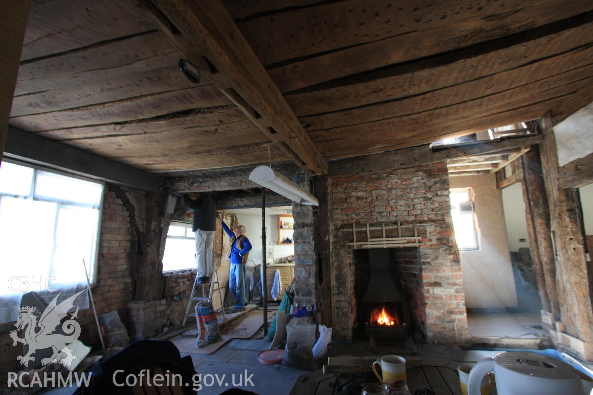 Colour photograph showing red brick fireplace, with reused timber for bressummer. Also showing girt beam with peg holes indicating stud locations at Porth-y-Dwr, 67 Clwyd Street, Ruthin. Photographed during survey conducted by Geoff Ward on 10th June 2013.