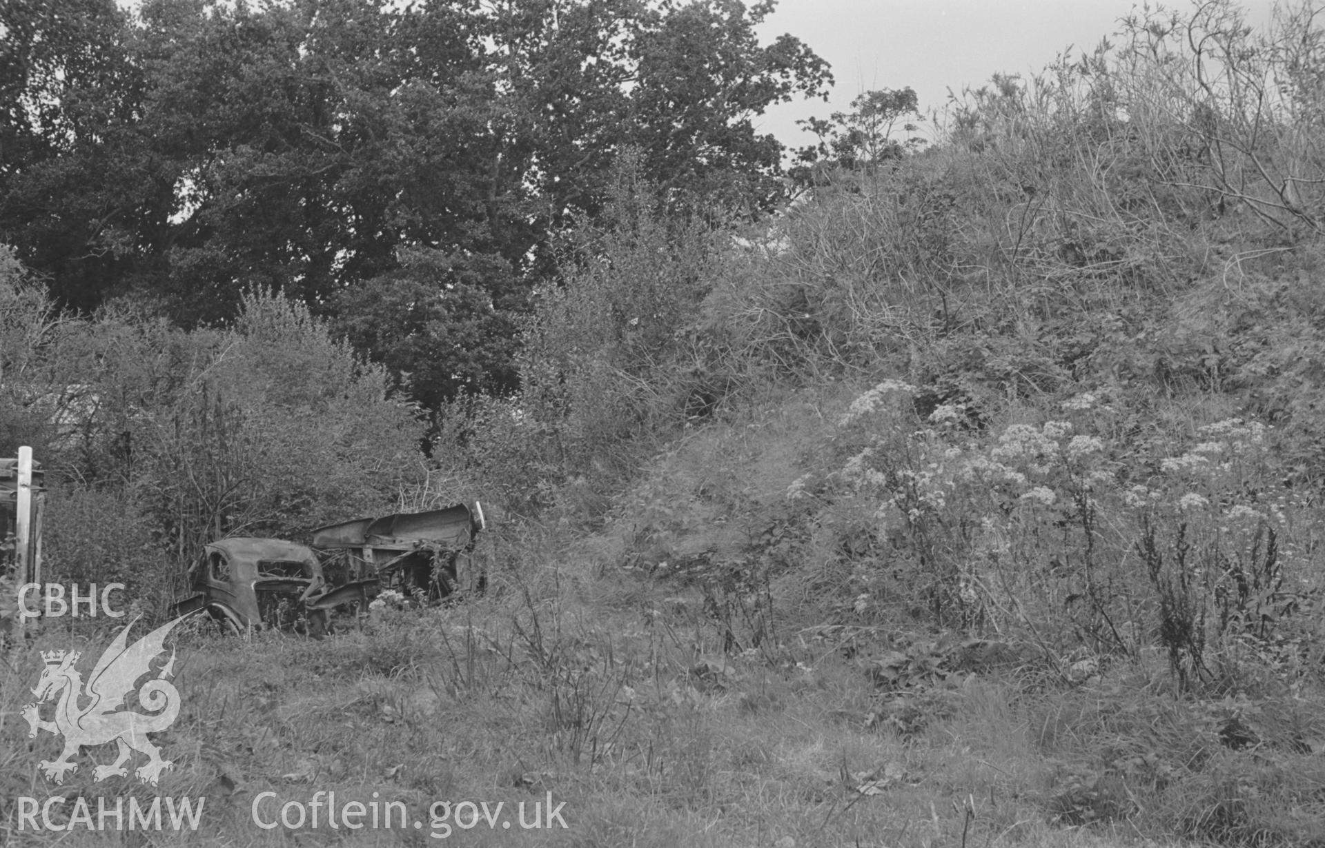 Digital copy of a black and white negative showing view along the north western side of the Norman motte of Castell Ddol-Wlff, Llanybydder. Photographed in September 1963 by Arthur O. Chater from Grid Reference SN 5200 4453, looking east north east.