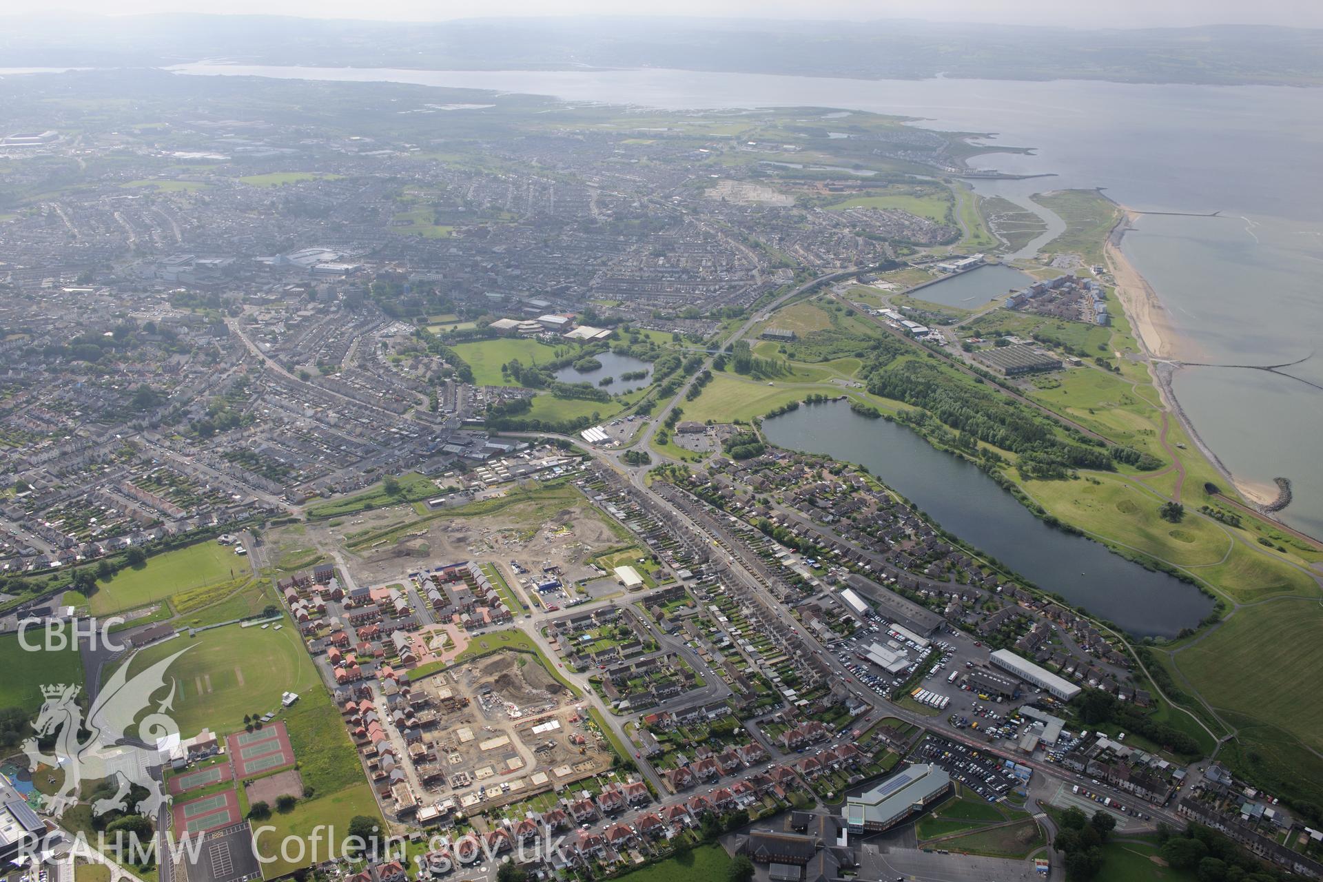 View of the town of Llanelli including the north dock; a new housing estate on the site of the old Stradey Park rugby stadium and Ysgol Gyfun y Strade (just visible, bottom left). Oblique aerial photograph taken during the Royal Commission's programme of archaeological aerial reconnaissance by Toby Driver on 15th June 2015.
