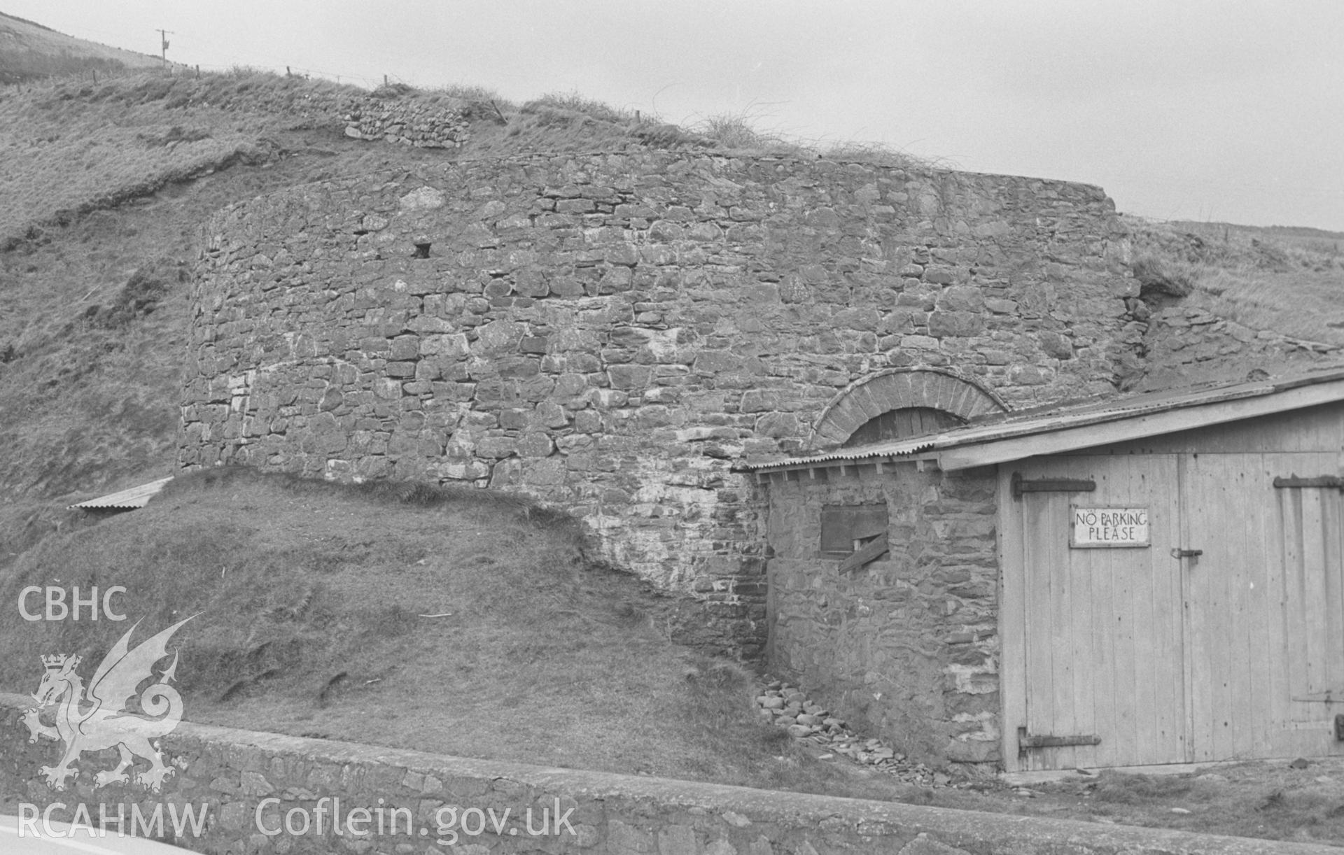 Digital copy of a black and white negative showing a disused limekiln and wooden shed just above the beach at Cwmtydu, south west of New Quay. Photographed by Arthur O. Chater in April 1966 from Grid Reference SN 355 576, looking south east.