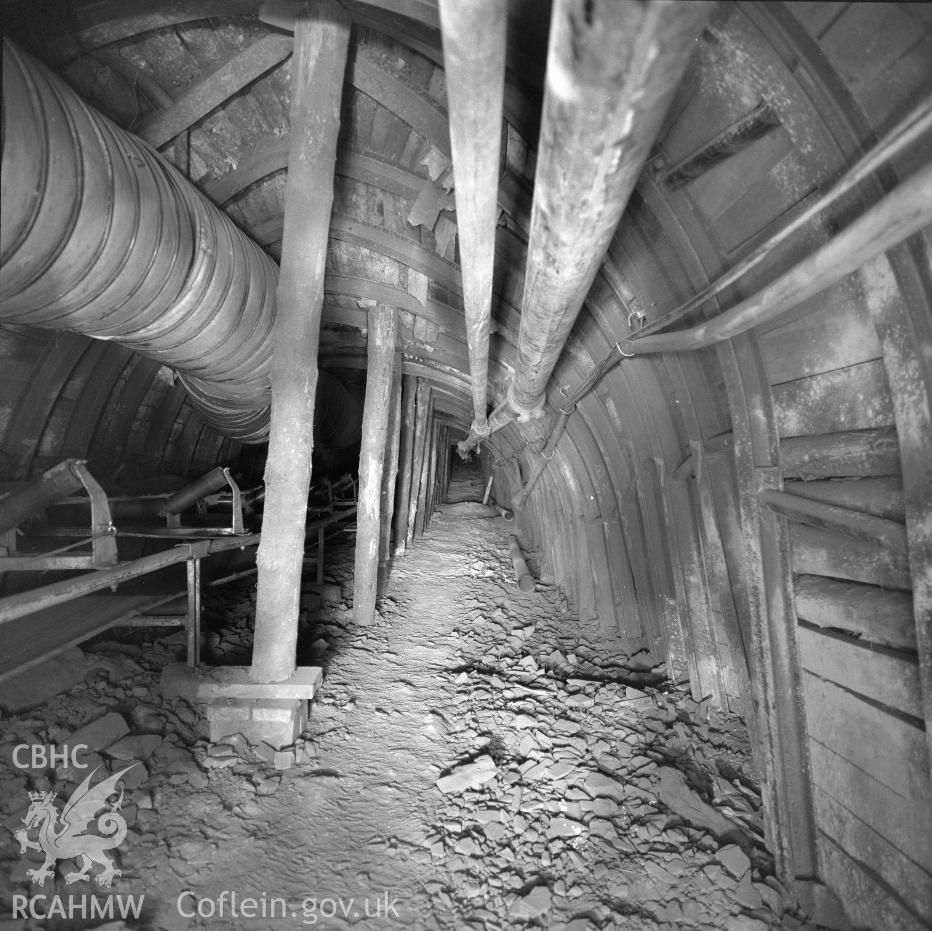 Digital copy of an acetate negative showing timbering on a fault in a main trunk road with conveyor at Taff Colliery, from the John Cornwell Collection.
