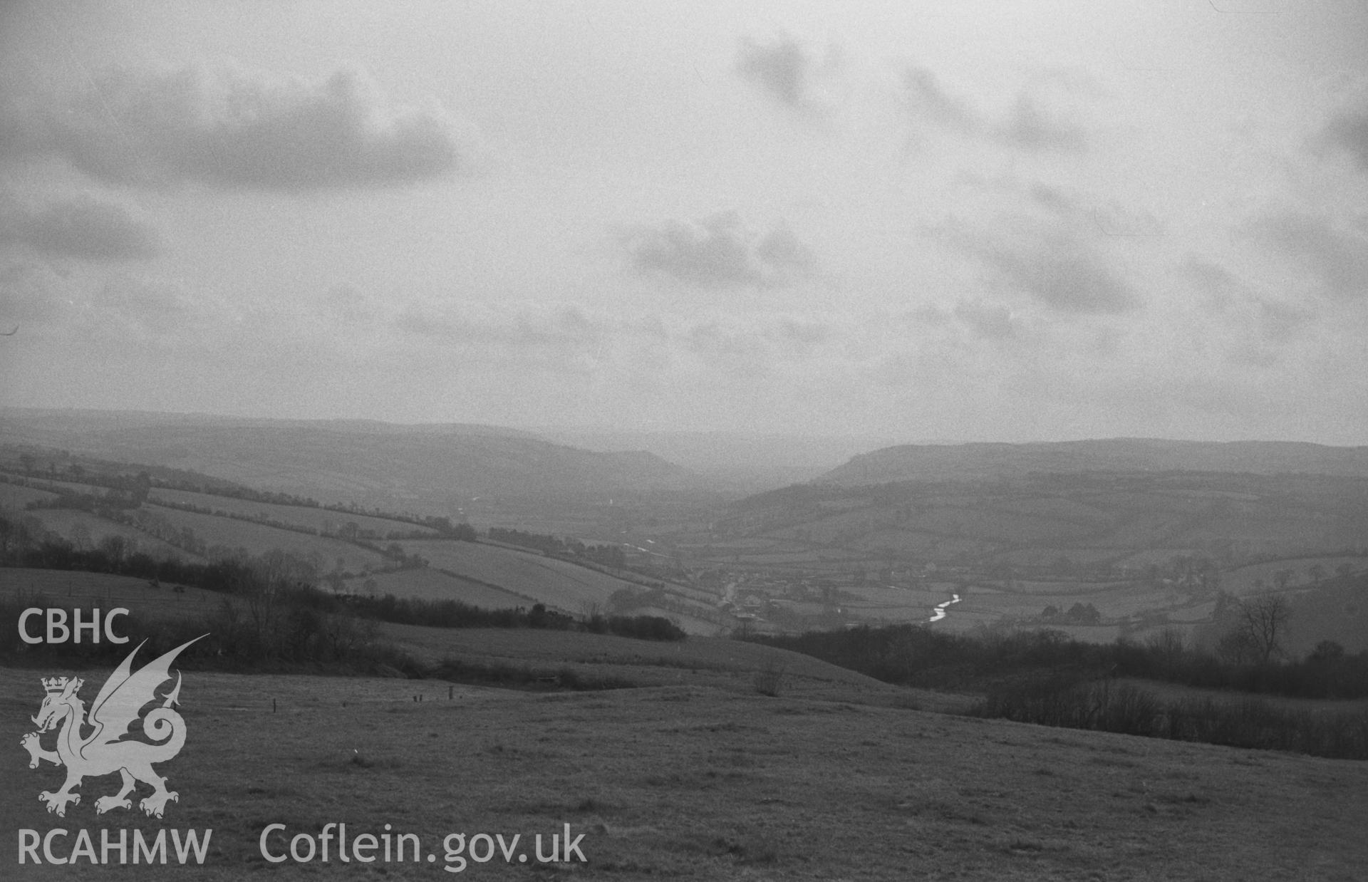Digital copy of black & white negative showing view across the Aeron valley from bank just across the lane from St. Padarns churchyard, Llanbadarn Odyn. Photographed in April 1964 by Arthur O. Chater from Grid Ref SN 6338 6048, looking west south west.