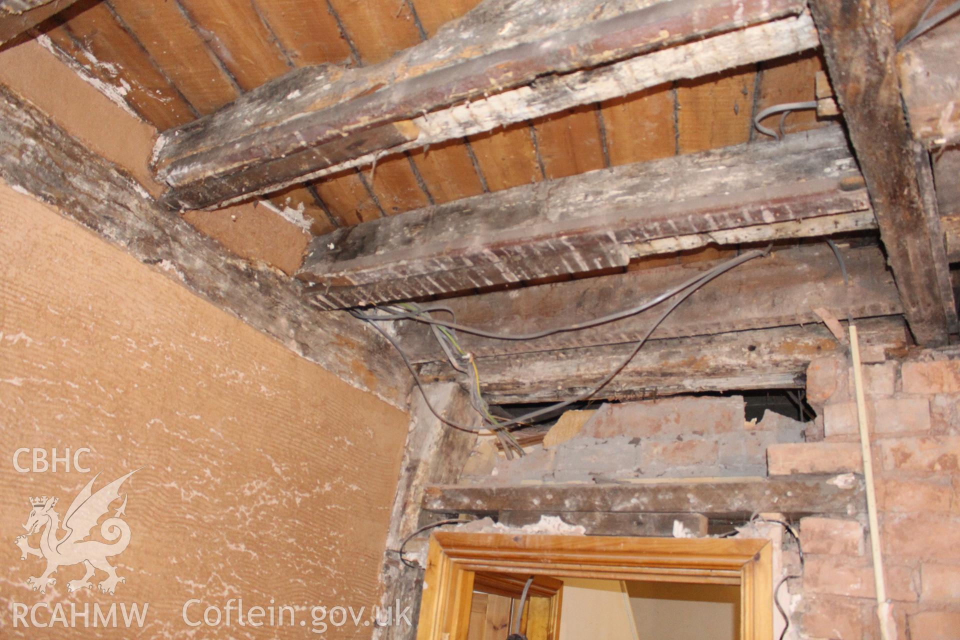 Colour photograph showing interior red brick wall and modern wooden door frame and ceiling beams at Porth y Dwr, Clwyd Street, Ruthin. Photograph taken during survey conducted by Geoff Ward on 9th October 2014.