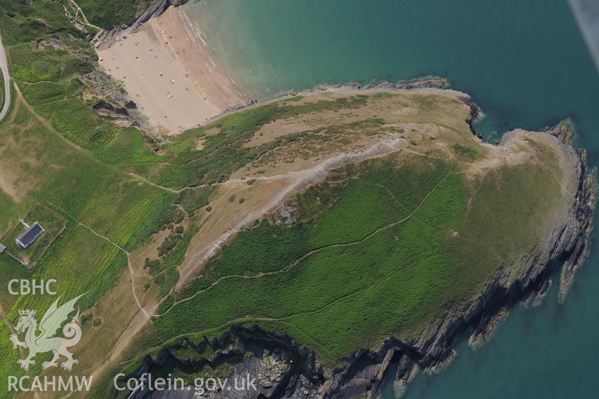 Holy Cross Church, the landing place on Traeth Mwnt and possible hillfort Foel y Mwnt, north of Cardigan. Oblique aerial photograph taken during the Royal Commission?s programme of archaeological aerial reconnaissance by Toby Driver on 12th July 2013.