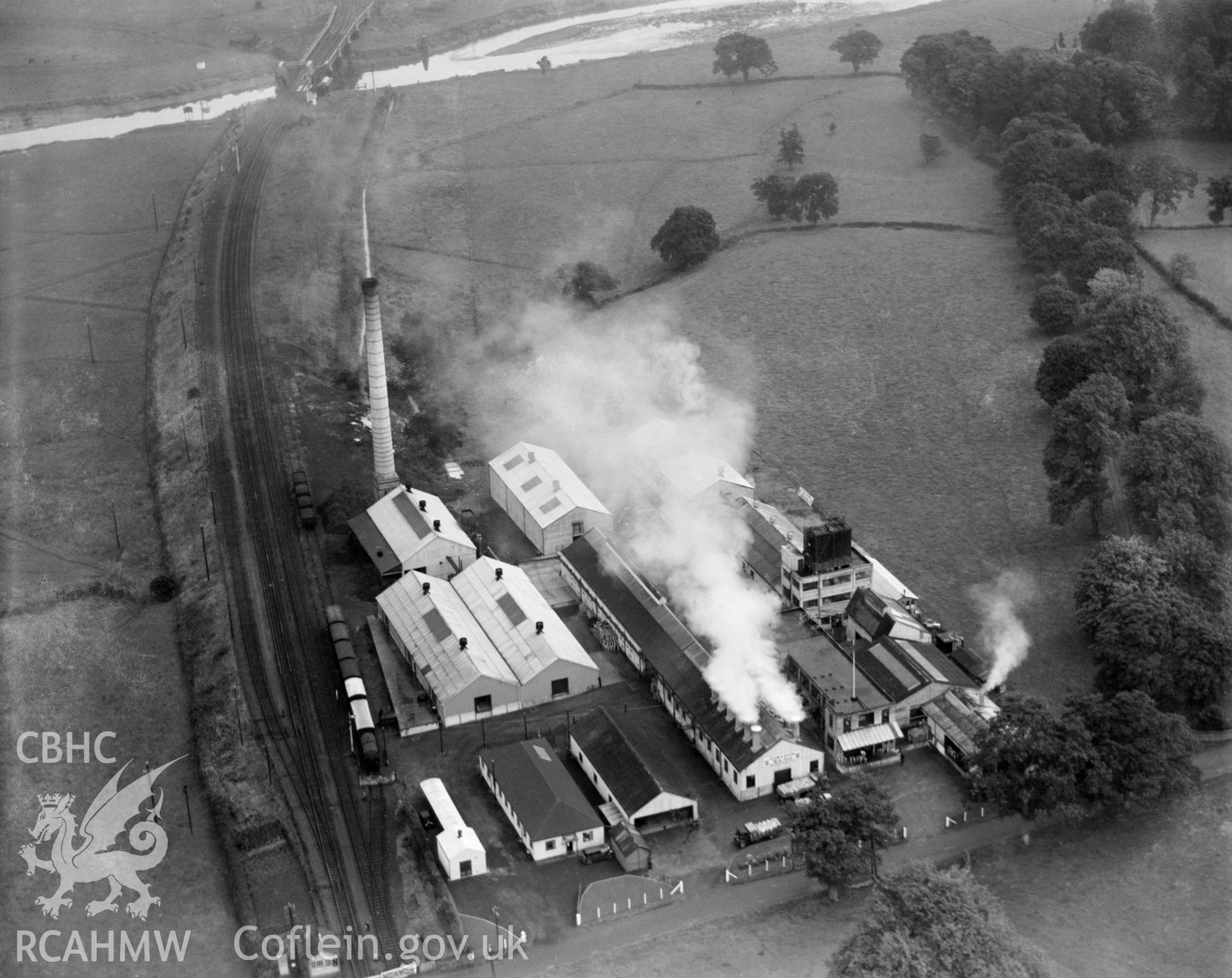 Digital copy of a black and white, oblique aerial photograph of the Cow & Gate milk factory in Carmarthen. The photograph shows a view from the West.