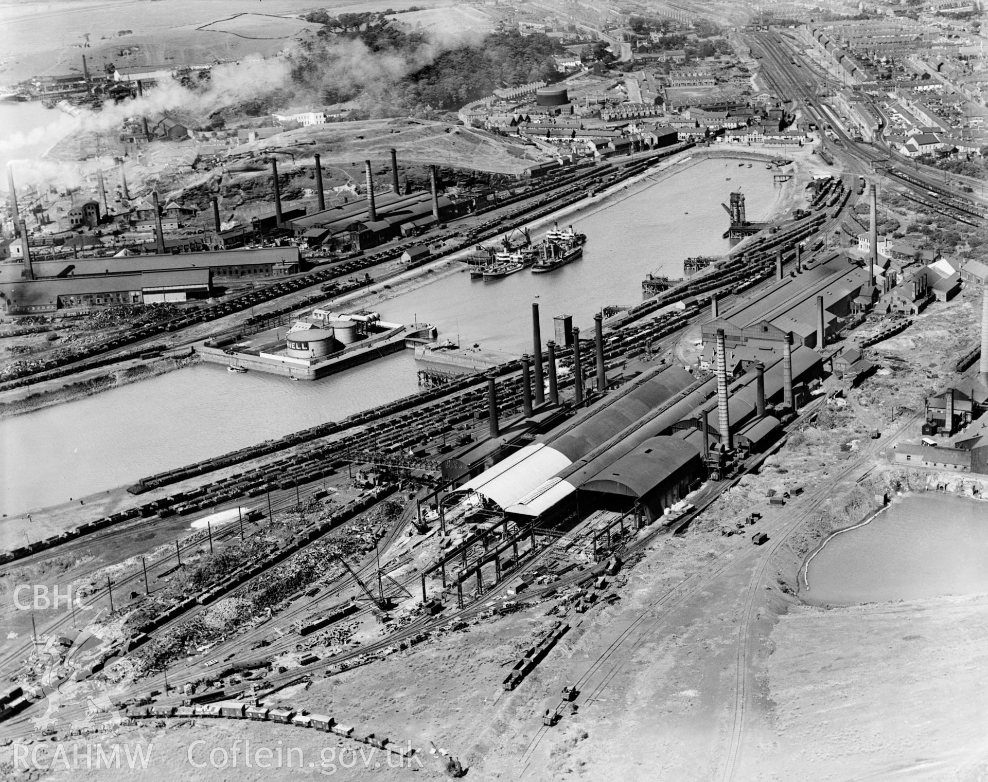 View of Briton Ferry Dock showing Baglan Bay Tinplate Co., Briton Ferry Steel Works, Albion Steelworks, Gwalia & Victoria Tinplate Works and Whitford Works from the south, oblique aerial view. 5?x4? black and white glass plate negative.