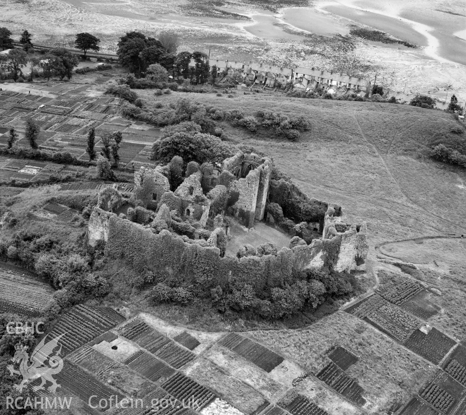 Digital copy of a black and white, oblique aerial photograph of Oystermouth Castle, Glamorgan. The photograph shows a view from the South West. The allotment gardens are still in use and the castle has benefitted from the removal of much of the vegetation and repair and restoration of the stonework.