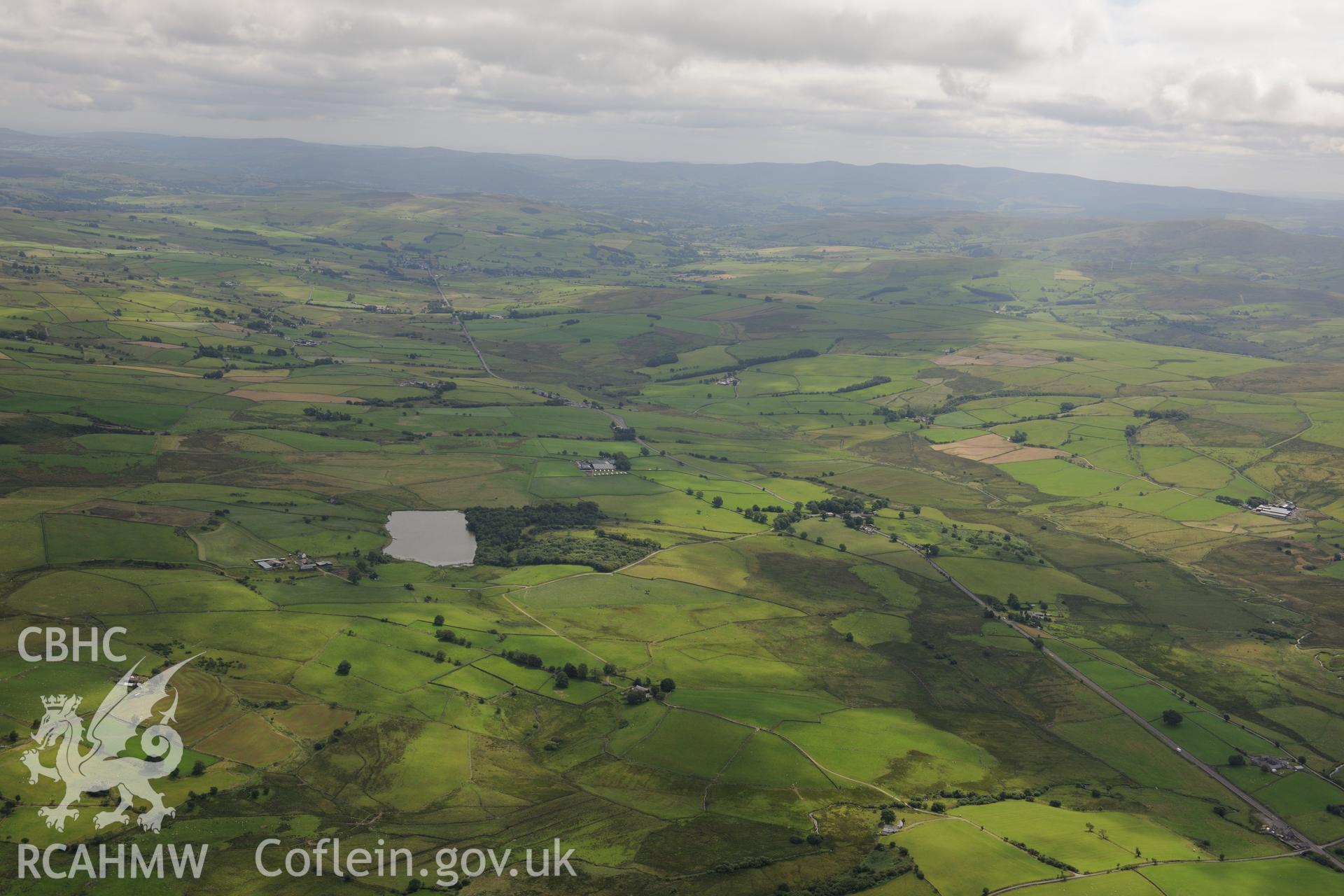 Llyn y Cwrt lake, Llyn y Cwrt farmhouse and Bryn Heilyn house. Oblique aerial photograph taken during the Royal Commission's programme of archaeological aerial reconnaissance by Toby Driver on 30th July 2015.