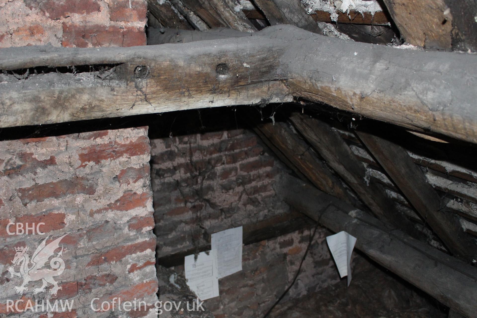 Colour photograph showing detail of brick wall and timber roof frame at 5-7 Mwrog Street, Ruthin. Photographed during survey conducted by Geoff Ward on 14th May 2014.