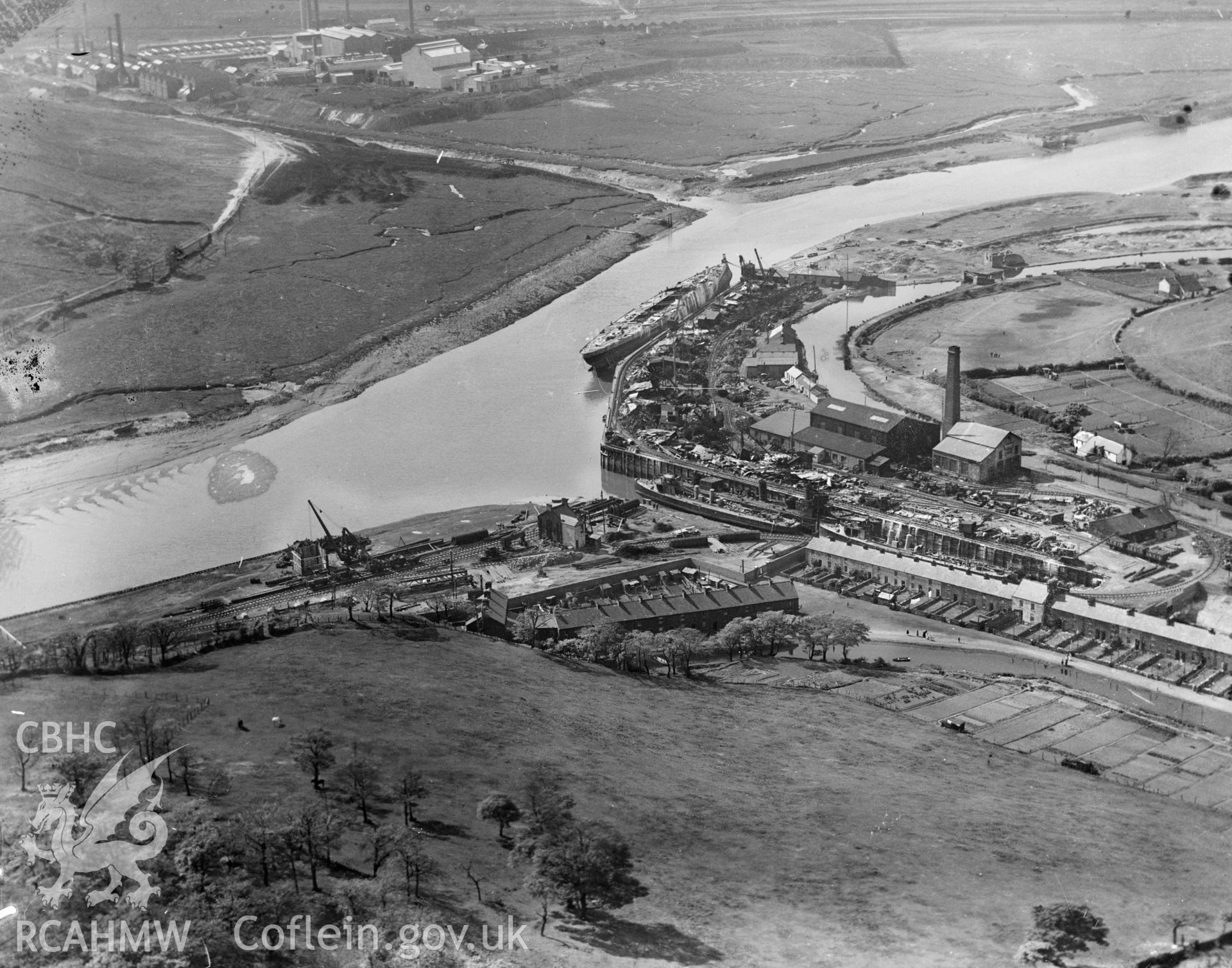 View of Briton Ferry dock showing naval vessel in process of being scrapped, oblique aerial view. 5?x4? black and white glass plate negative.