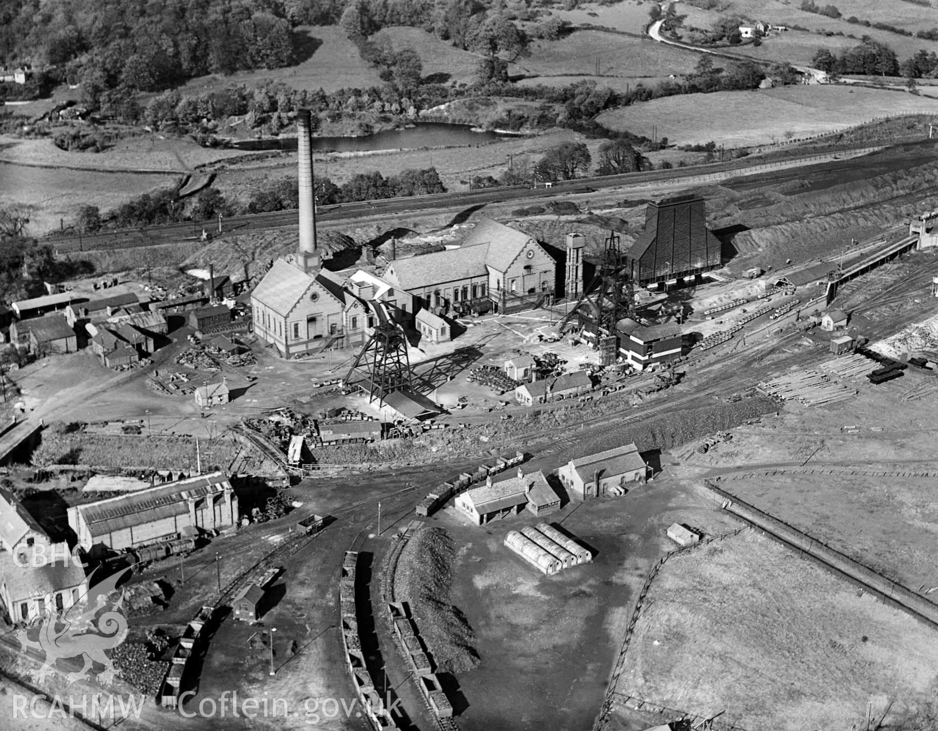 Digital copy of a black and white, oblique aerial photograph of Gresford Colliery. The photograph shows the view from the south east, taken one month after one of the worst mining disasters in the country on 22nd September, 1934, when a major explosion and subsequent fire in the Dennis section killed 266 miners. There are no obvious signs of damage at the surface and no signs of any activity whatsoever. Photograph taken by Aero Pictorial Ltd.