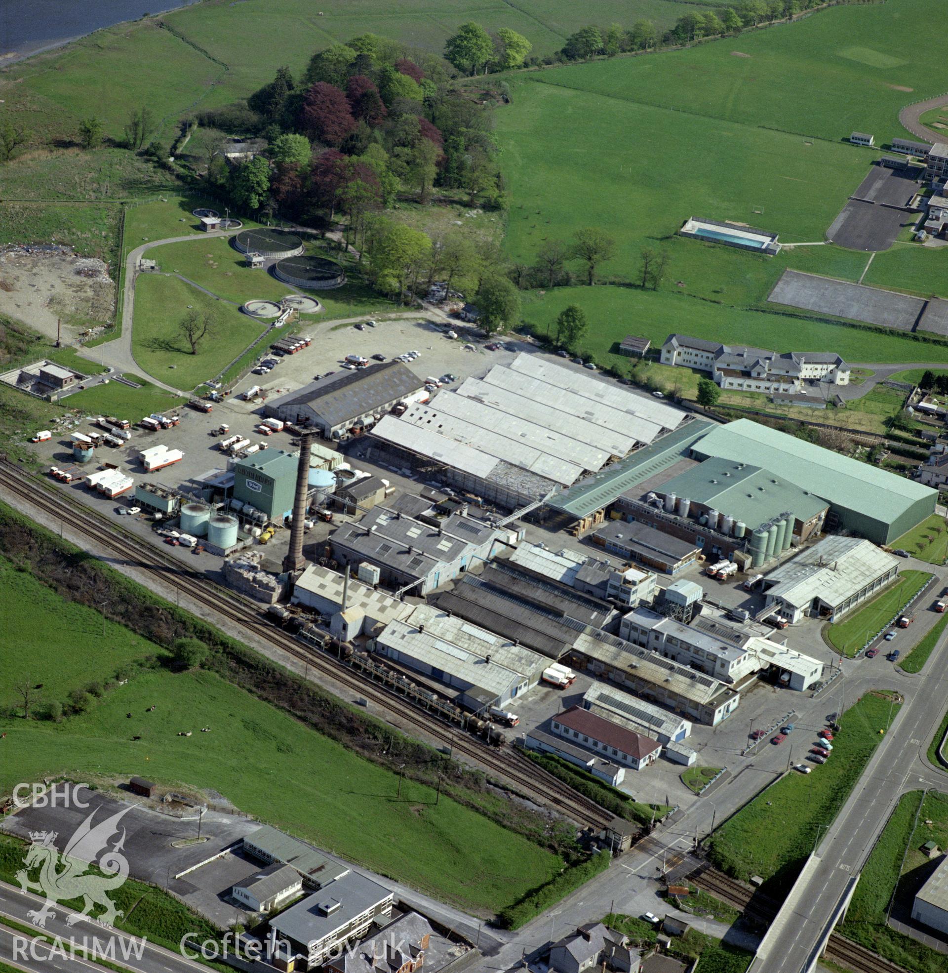 Digital copy of a colour oblique aerial photograph of the Milk factory, Carmarthen. The photograph shows a view from the North West, showing the original Cow & Gate milk factory in the foreground and the later St. Ivel creamery to the South.