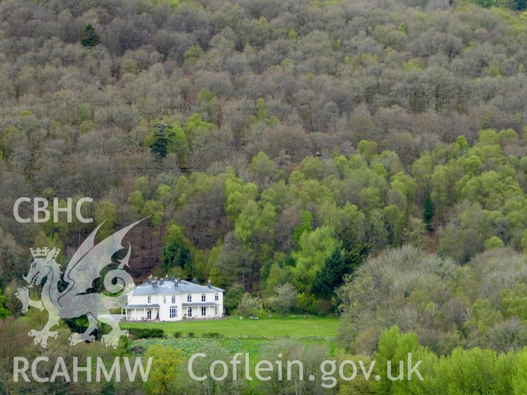 Colour photo of Dol-llys, Llanidloes, showing a distant view with the lawn and Pen yr Allt Wood behind taken by Mal Shears during April 2017.