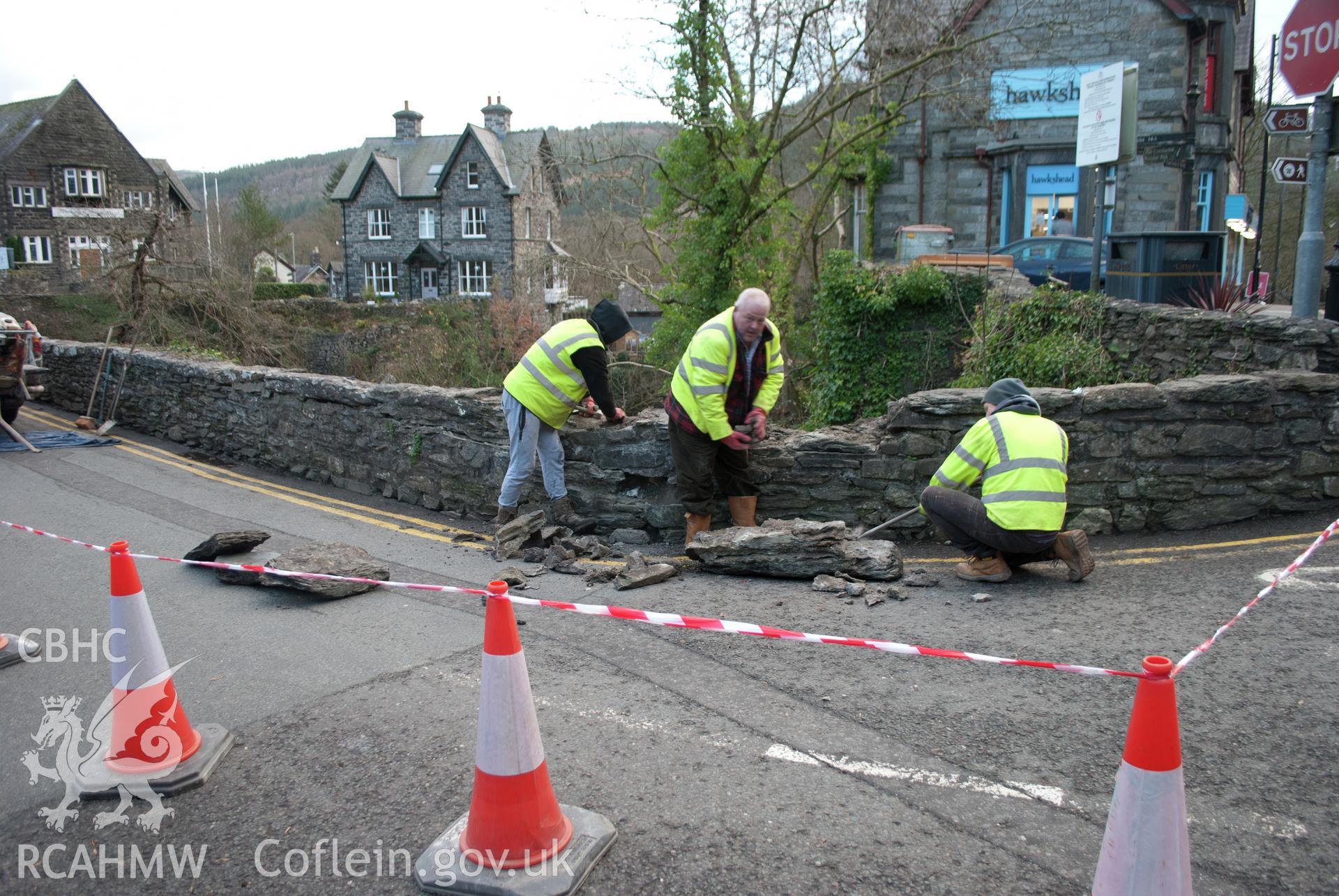 Action shot from the west showing demolition work (by hand) taking place at the southeast corner of the parapet. Digital photograph taken for Archaeological Watching Brief at Pont y Pair, Betws y Coed, 2019. Gwynedd Archaeological Trust Project no. G2587.