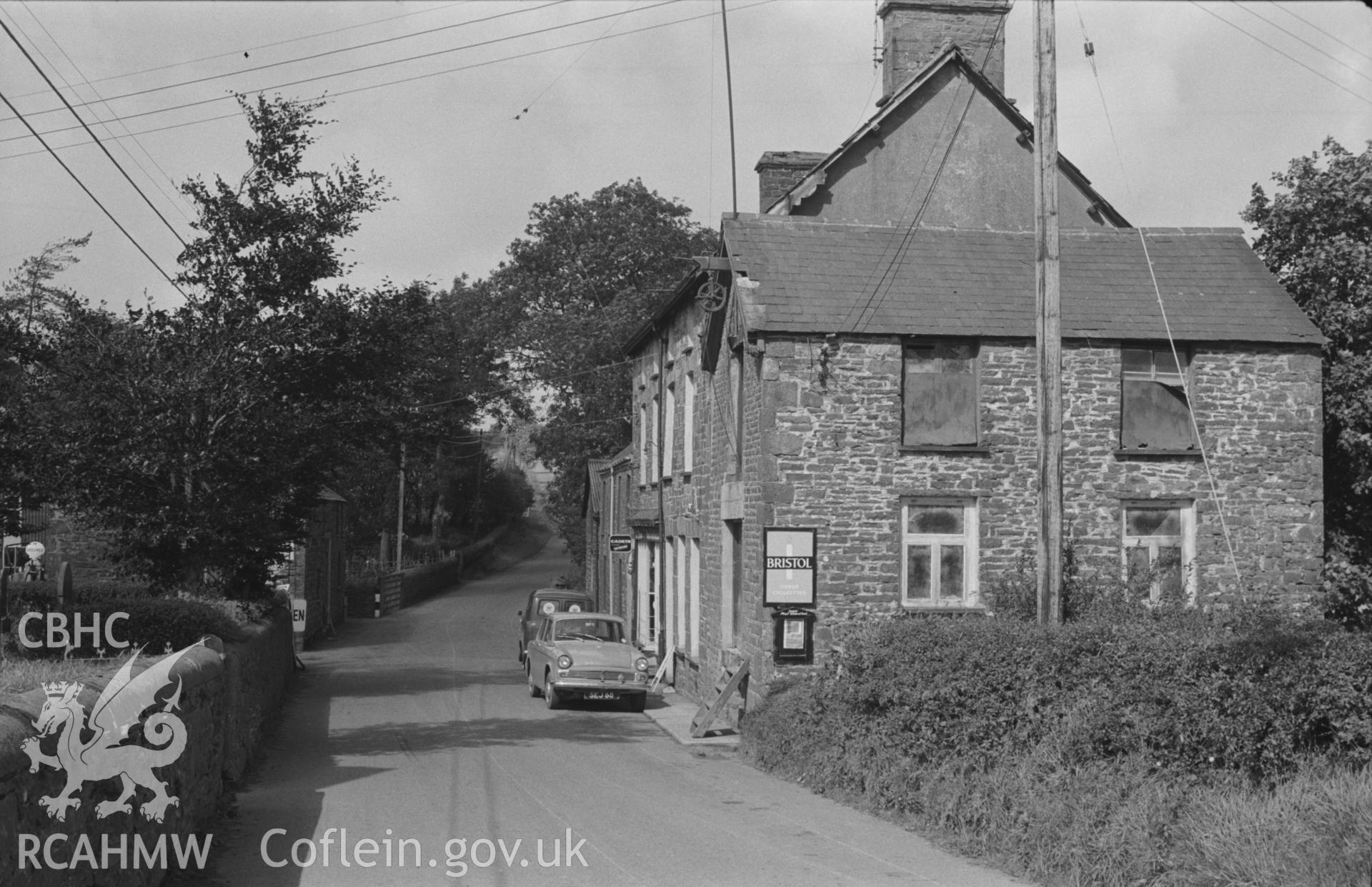 Digital copy of a black and white negative showing Bronant village shop and garage, Lledrod, looking along the A485 road. Warehouse with pulley on right. Photographed by Arthur O. Chater in September 1966 looking north from Grid Reference SN 641 677.