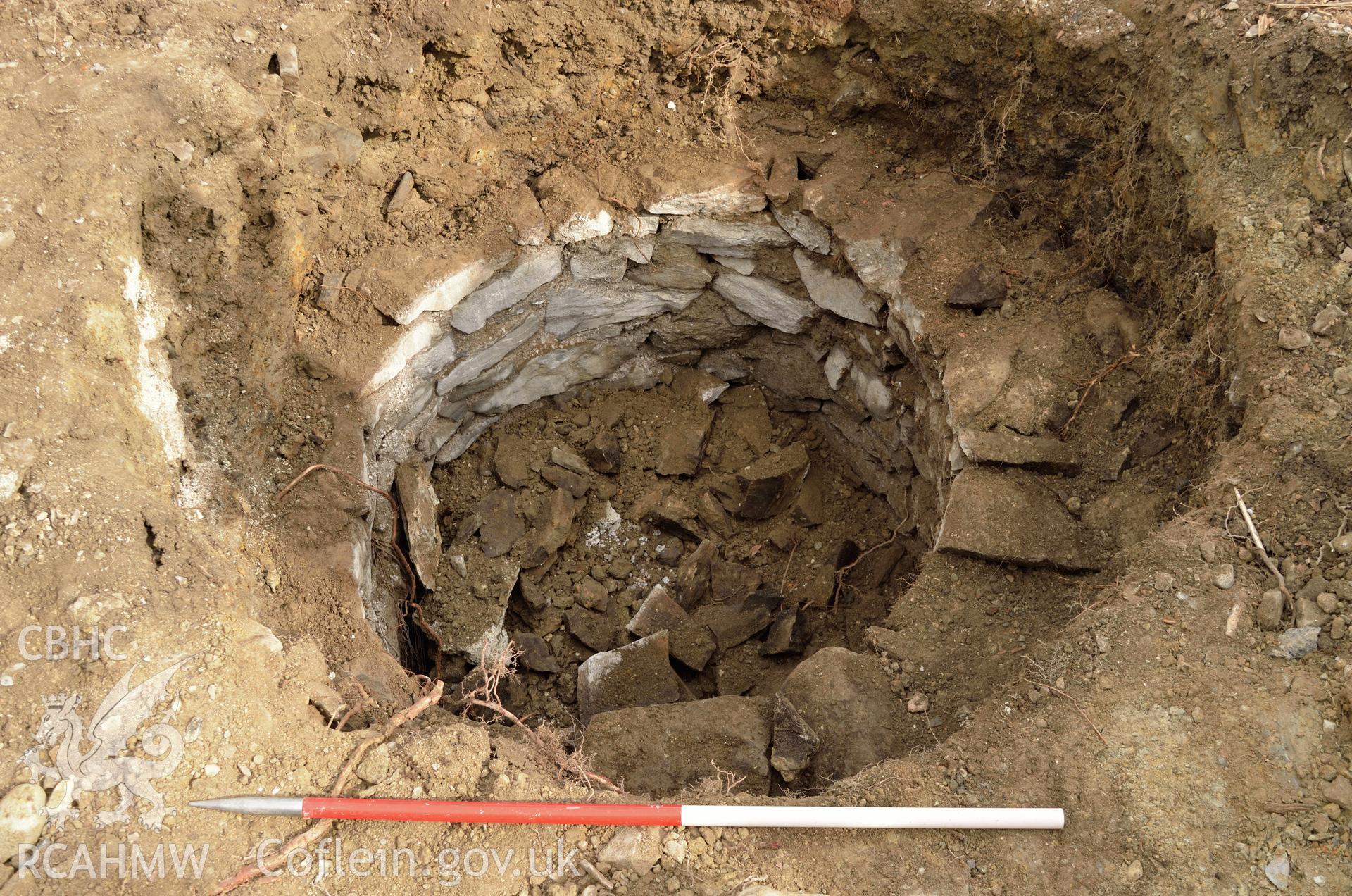 'Cut of well after removal of top 0.5m of stone, viewed from the south east.' Photographed by Gwynedd Archaeological Trust as part of archaeological mitigation report for well at Plas Celynin, Henryd, Conwy, on 6th August 2018. Project no. G2568.