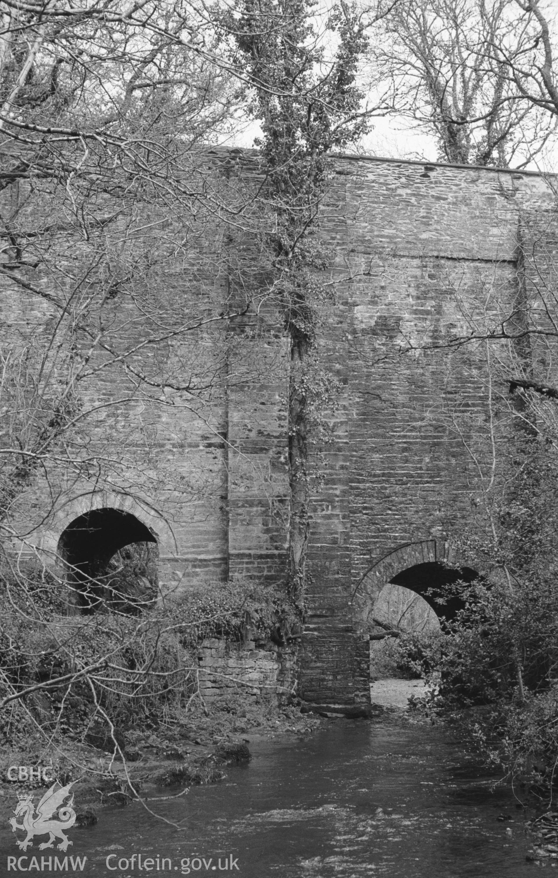 Digital copy of a black and white negative showing view looking up Nant Gwylan to the bridge on the Henllan-Llandyfriog road at Felin Cwrrws. Photographed by Arthur O. Chater in April 1966 from Grid Reference SN 354 412, looking east north east.