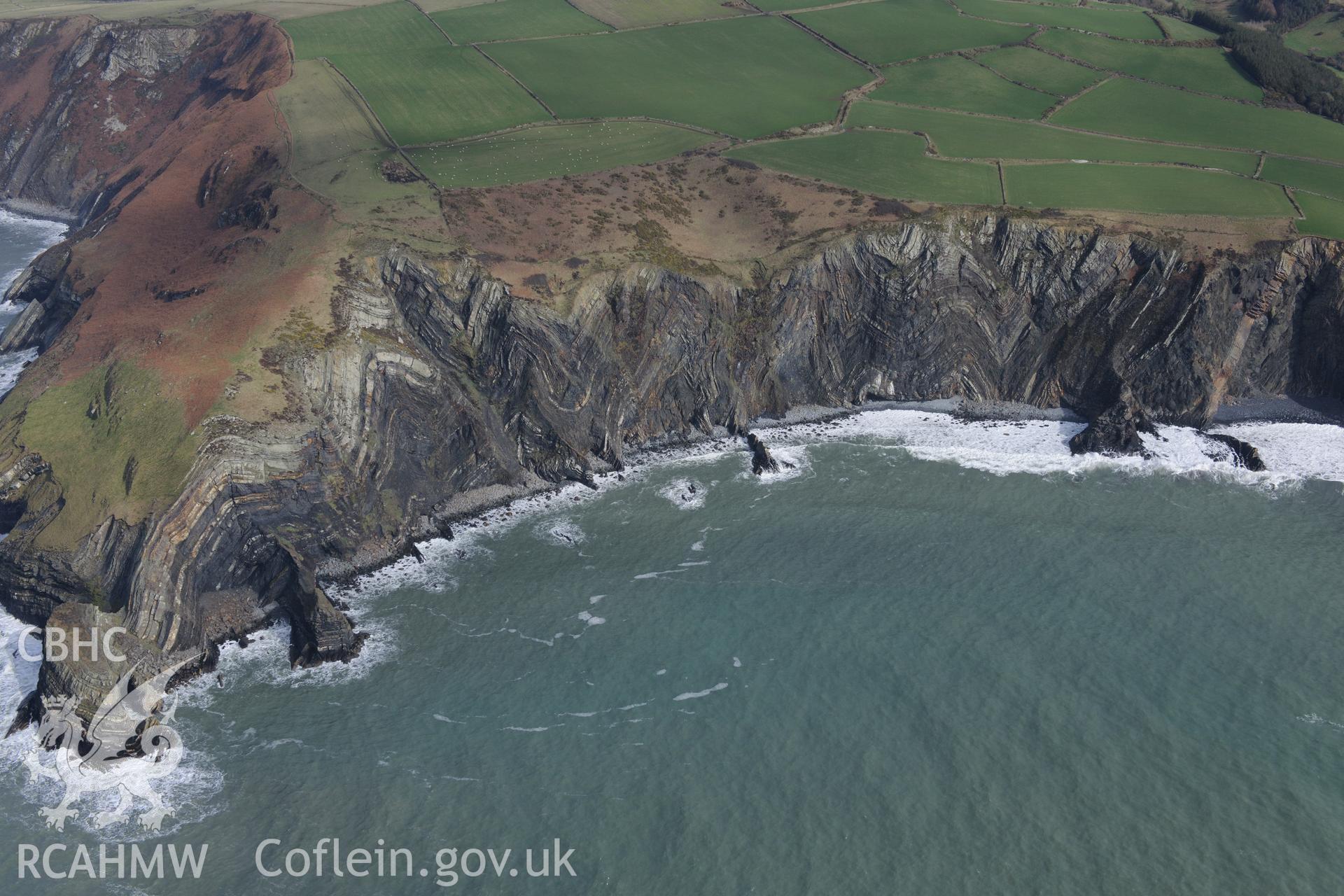 Visible strata in the rock face near Traeth y Rhedyn beach, north west of St. Dogmaels. The Pembrokeshire Coast Path follows the edges of the fields above. Oblique aerial photograph taken during the Royal Commission's programme of archaeological aerial reconnaissance by Toby Driver on 13th March 2015.