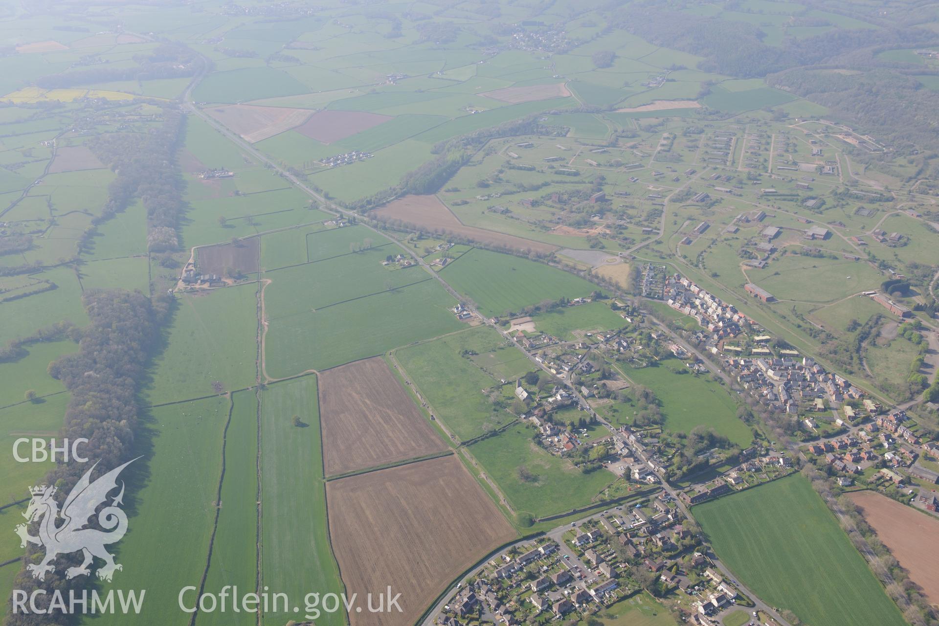 Caerwent village and Roman city including the Roman Amphitheatre and Basilica; St. Stephen's Church; the Motte, Caerwent House; Great House and West Gate Farm. Oblique aerial photograph taken during the Royal Commission's programme of archaeological aerial reconnaissance by Toby Driver on 21st April 2015.
