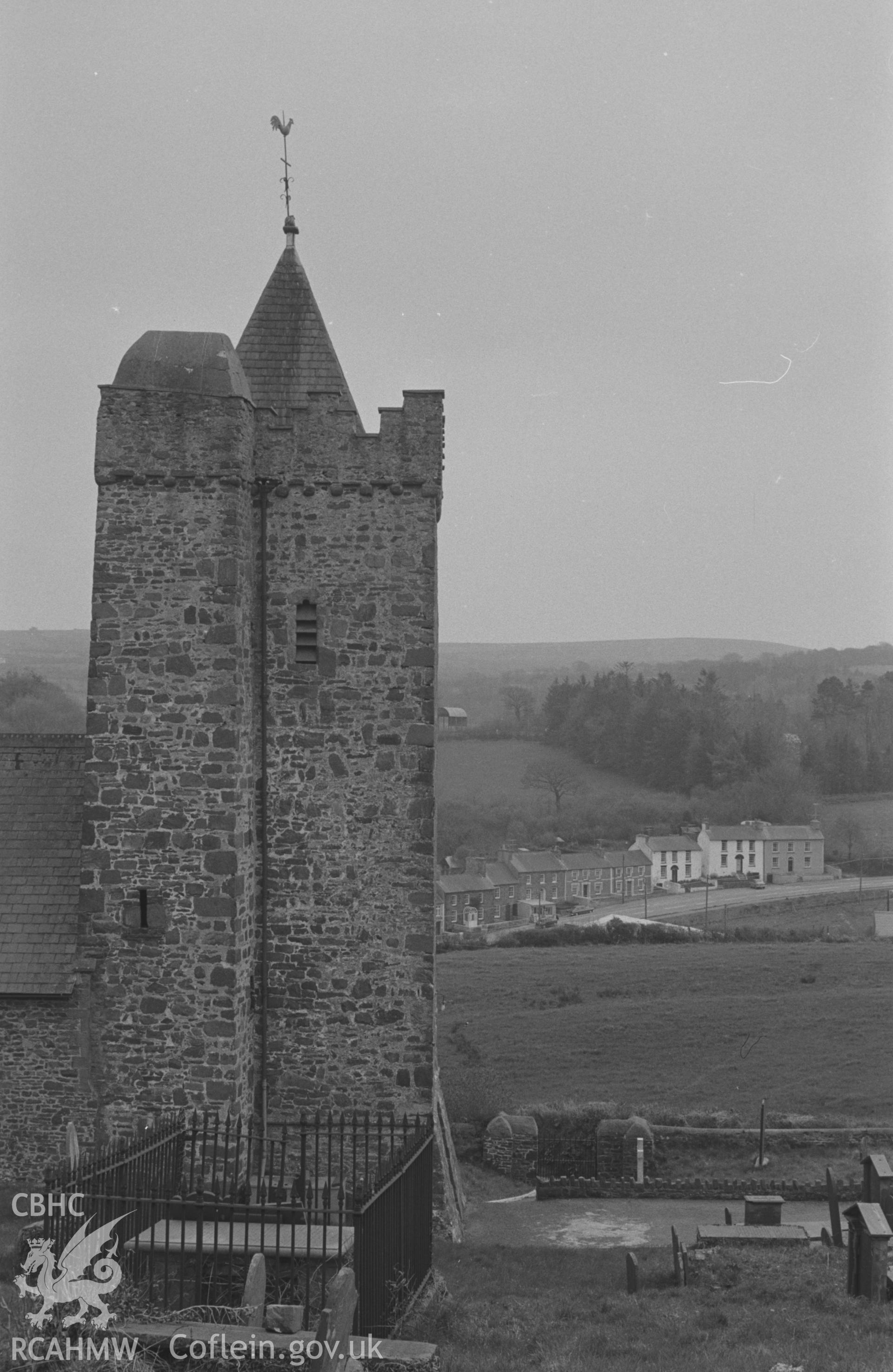 Digital copy of a black and white negative showing church tower at St. David's, with Llanarth main street in distance. Photographed by Arthur O. Chater on 13th April 1967, looking south from Grid Reference SN 423 578.