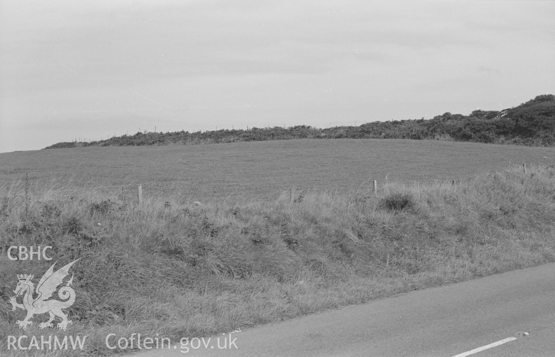 Digital copy of a black and white negative showing view of Castell Nadolig hillfort, Cardigan, with figure, car and haystack. Photographed in August 1963 by Arthur O. Chater from Grid Reference SN 2971 5025, looking north east.
