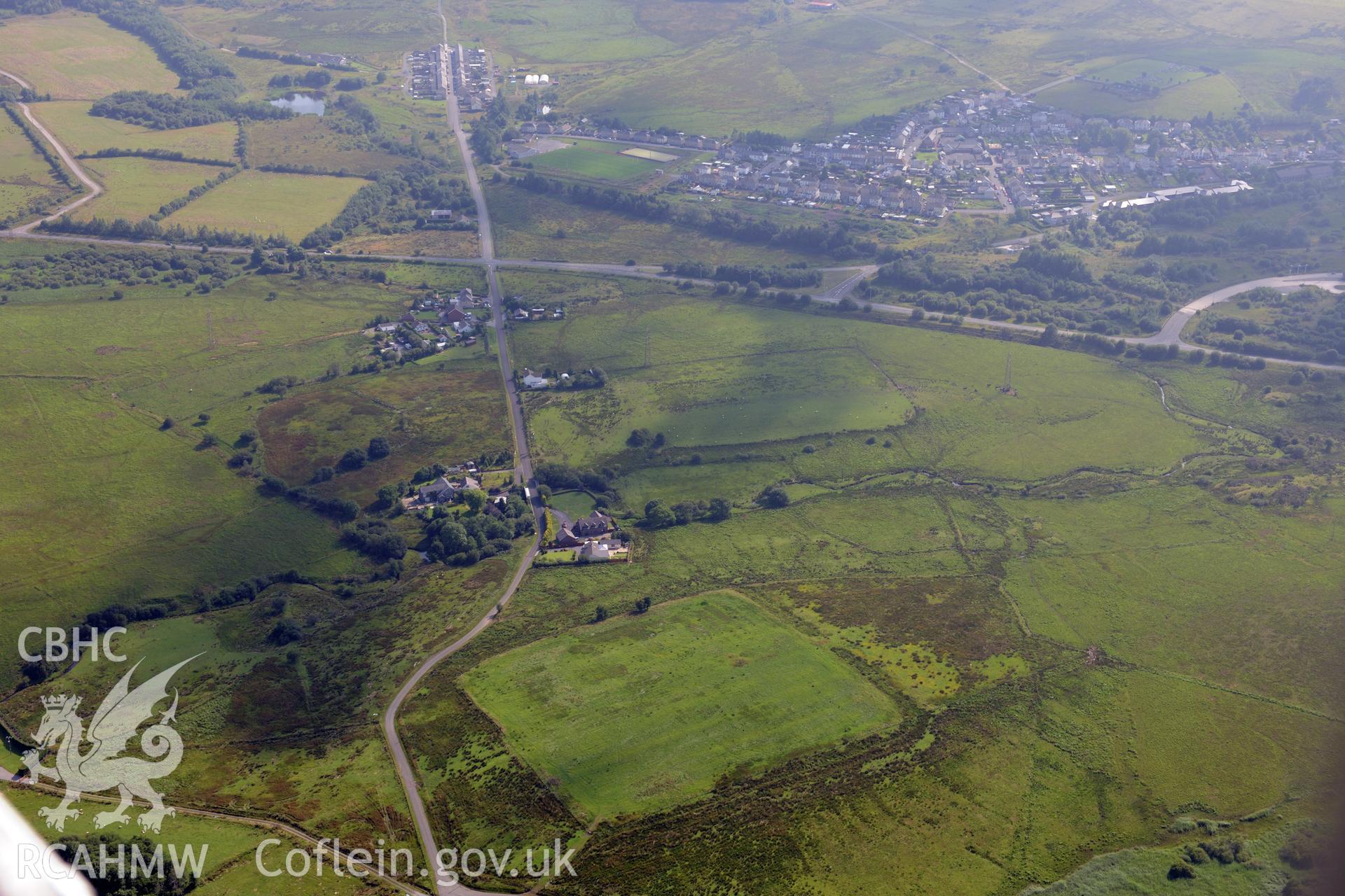 Coelbren roman fort and marching camp, with Dyffryn Cellwen village and Banwen industrial housing beyond, north east of Neath. Oblique aerial photograph taken during the Royal Commission?s programme of archaeological aerial reconnaissance by Toby Driver on 1st August 2013.