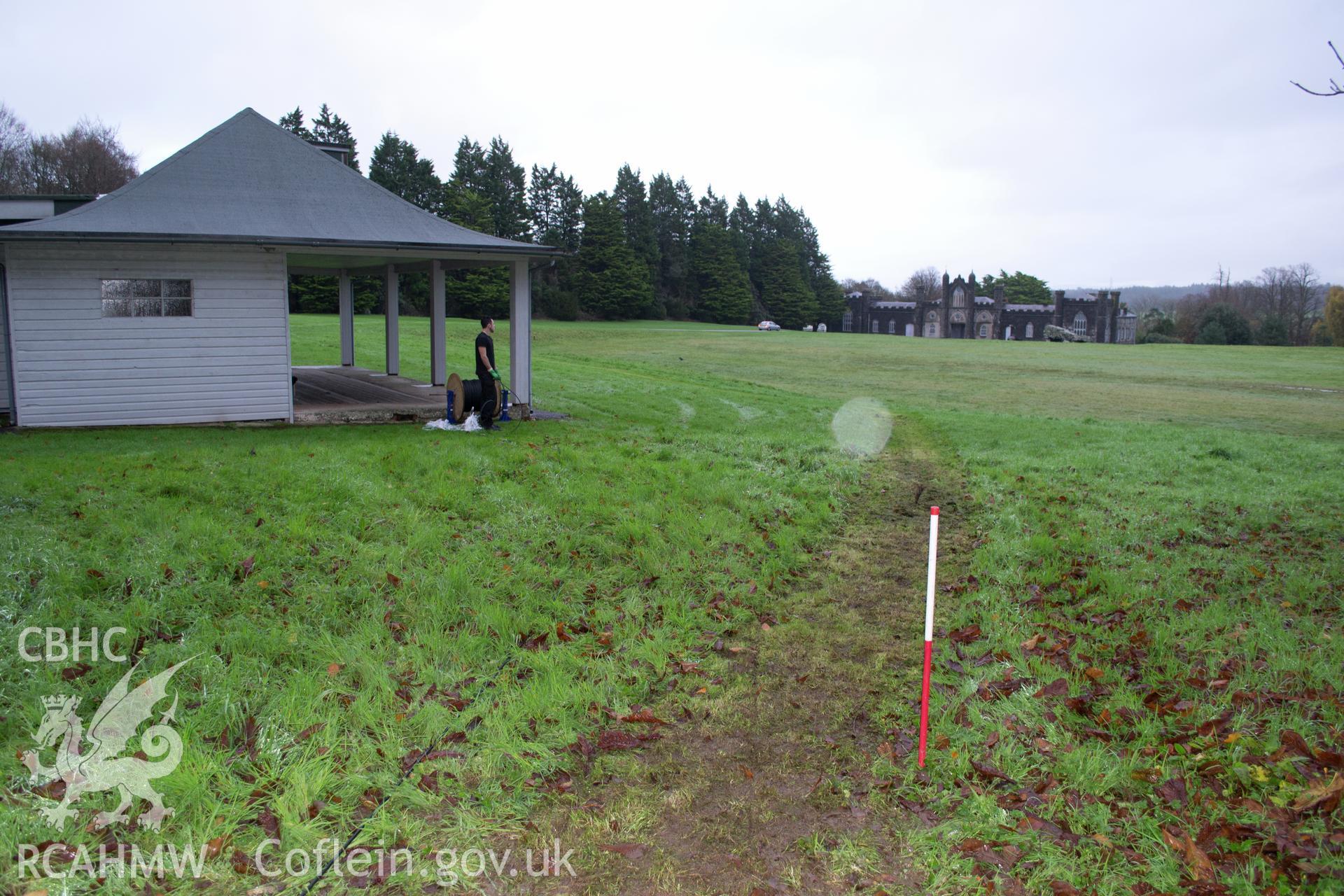 General view from south west along cable route, pre-excavation, showing pavilion & stable block in background. Photographed during watching brief of Plas Newydd, Ynys Mon, conducted by Gwynedd Archaeological Trust, 14/11/2017. Project no. 2542.