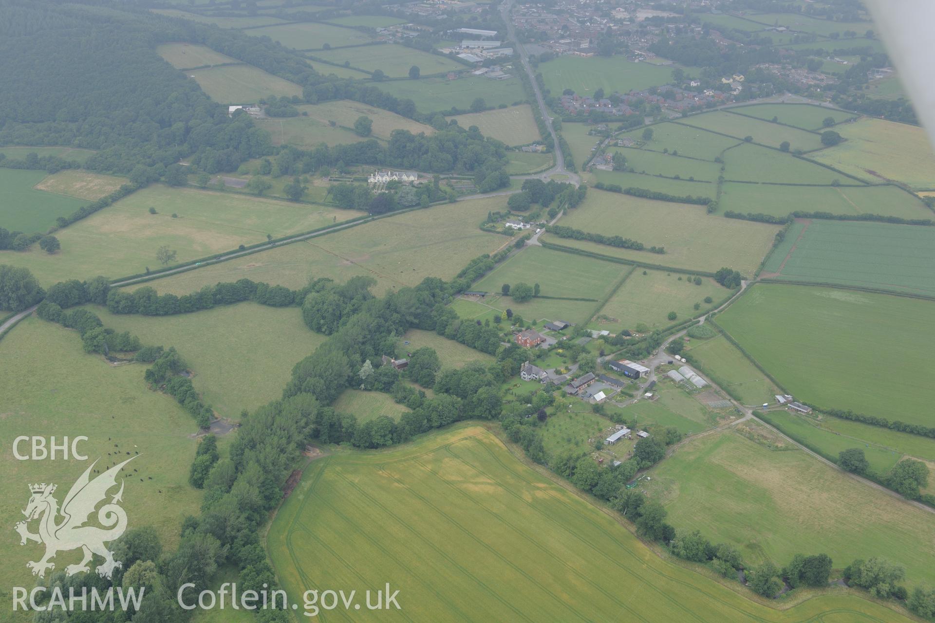 Wegnall farmhouse with the Wegnall cropmarks in the field below and the town of Presteigne in the distance. Oblique aerial photograph taken during the Royal Commission?s programme of archaeological aerial reconnaissance by Toby Driver on 1st August 2013.