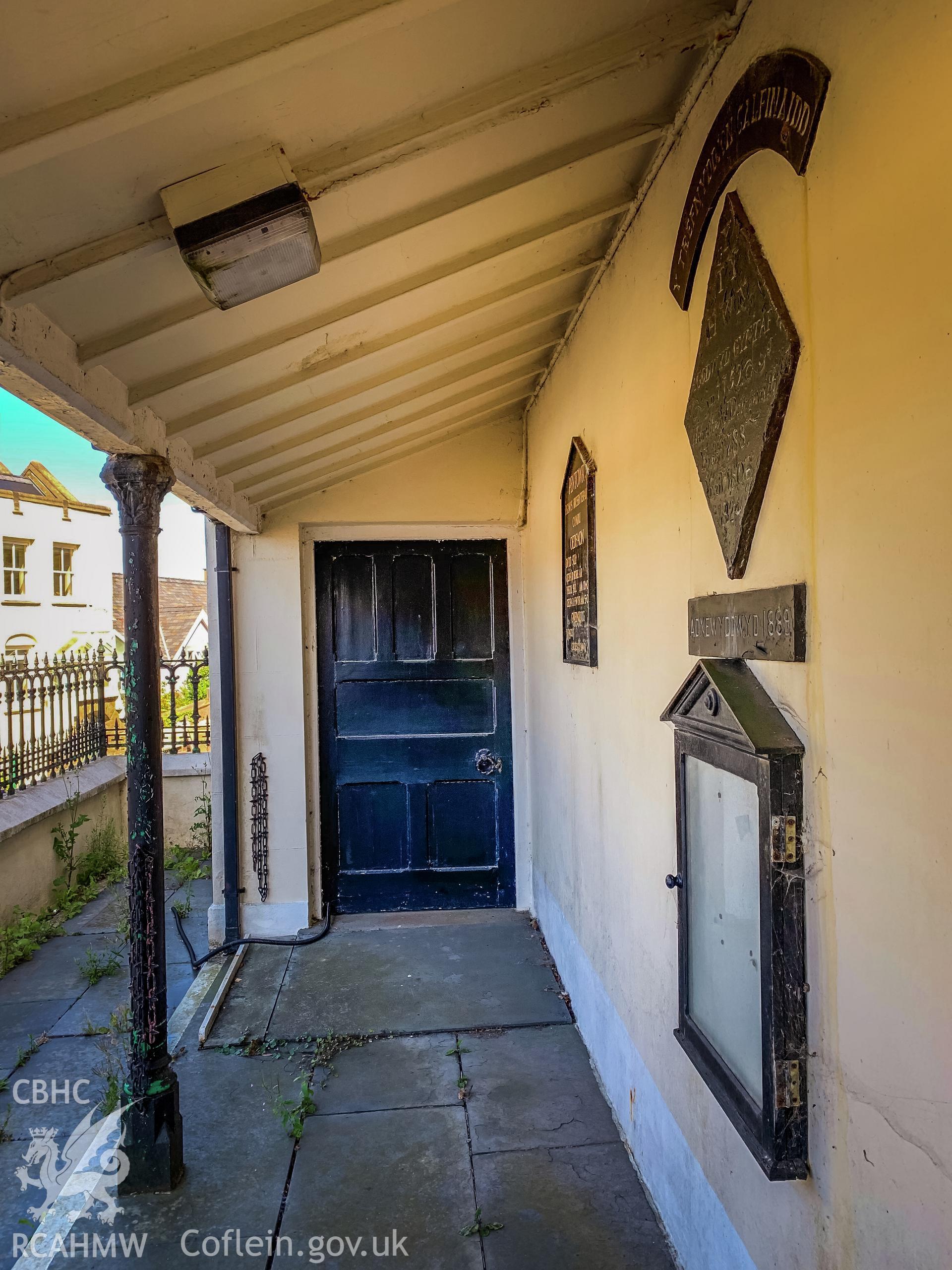 Digital colour photograph showing detailed view of exterior view of door, date stones and information board at Pentower Chapel, Fishguard, dated 2019. Photographed by Grace Elliott to meet a condition attached to a planning application.