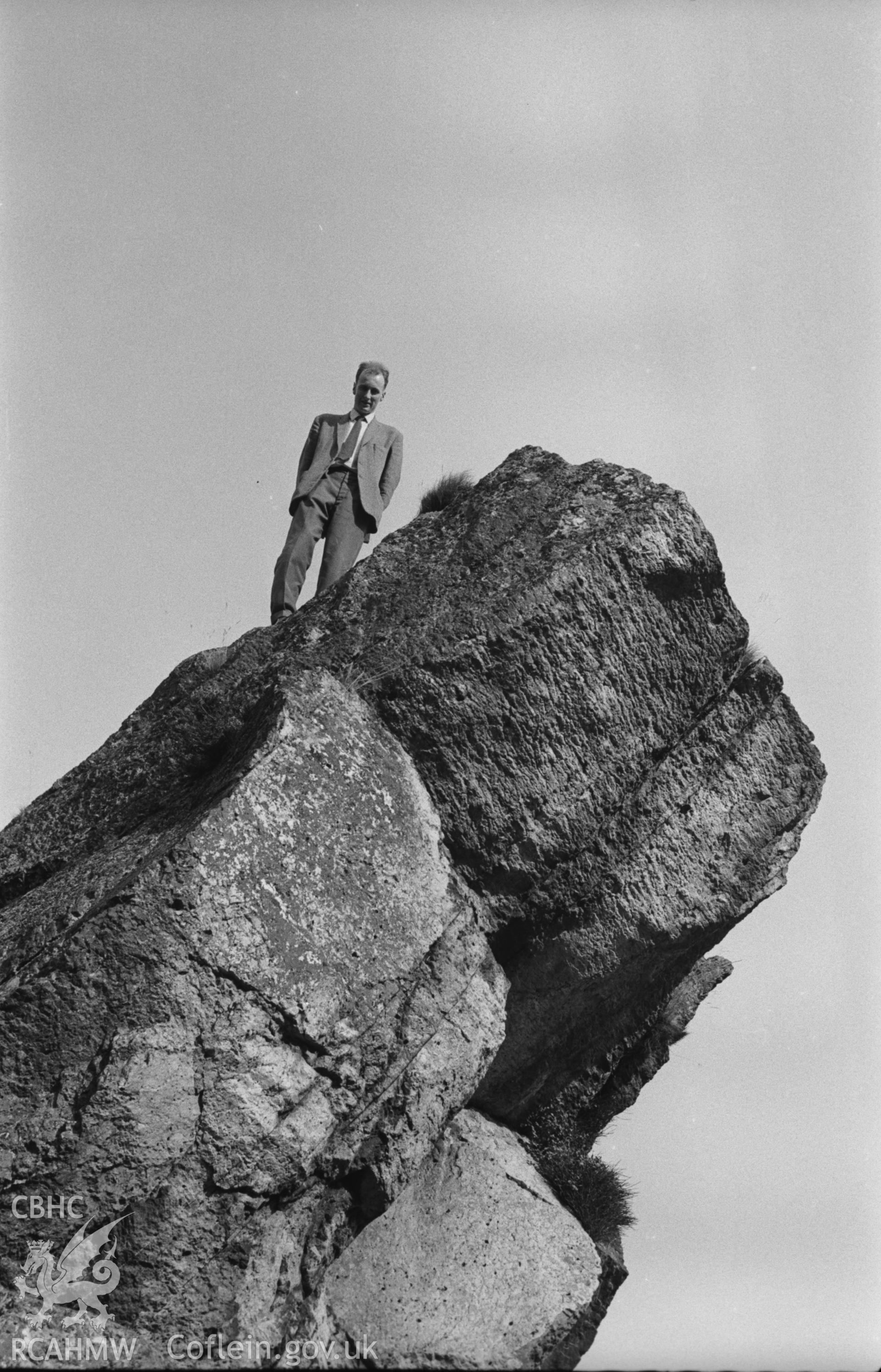 Digital copy of a black and white negative showing man on rock outcrop at Llanrhaeadr-ym-Mochnant. Photographed by Arthur O. Chater in September 1964.