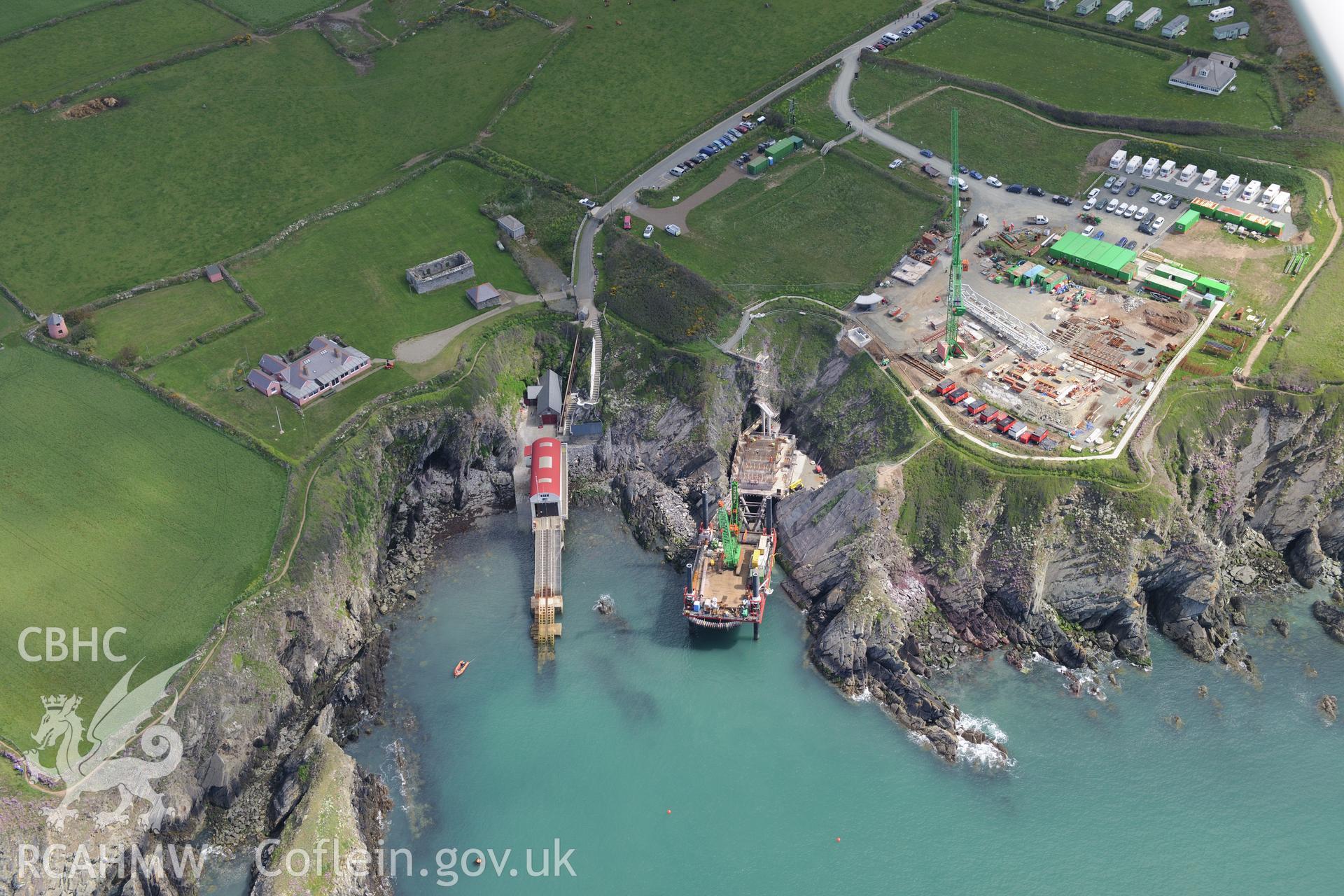 St Justinian's Chapel, St Justinian's bungalow, and St. David's old lifeboat station with the new station under construction. The floating mooring used by the crew whilst the station was being built is also visible. Oblique aerial photograph taken during the Royal Commission's programme of archaeological aerial reconnaissance by Toby Driver on 13th May 2015.