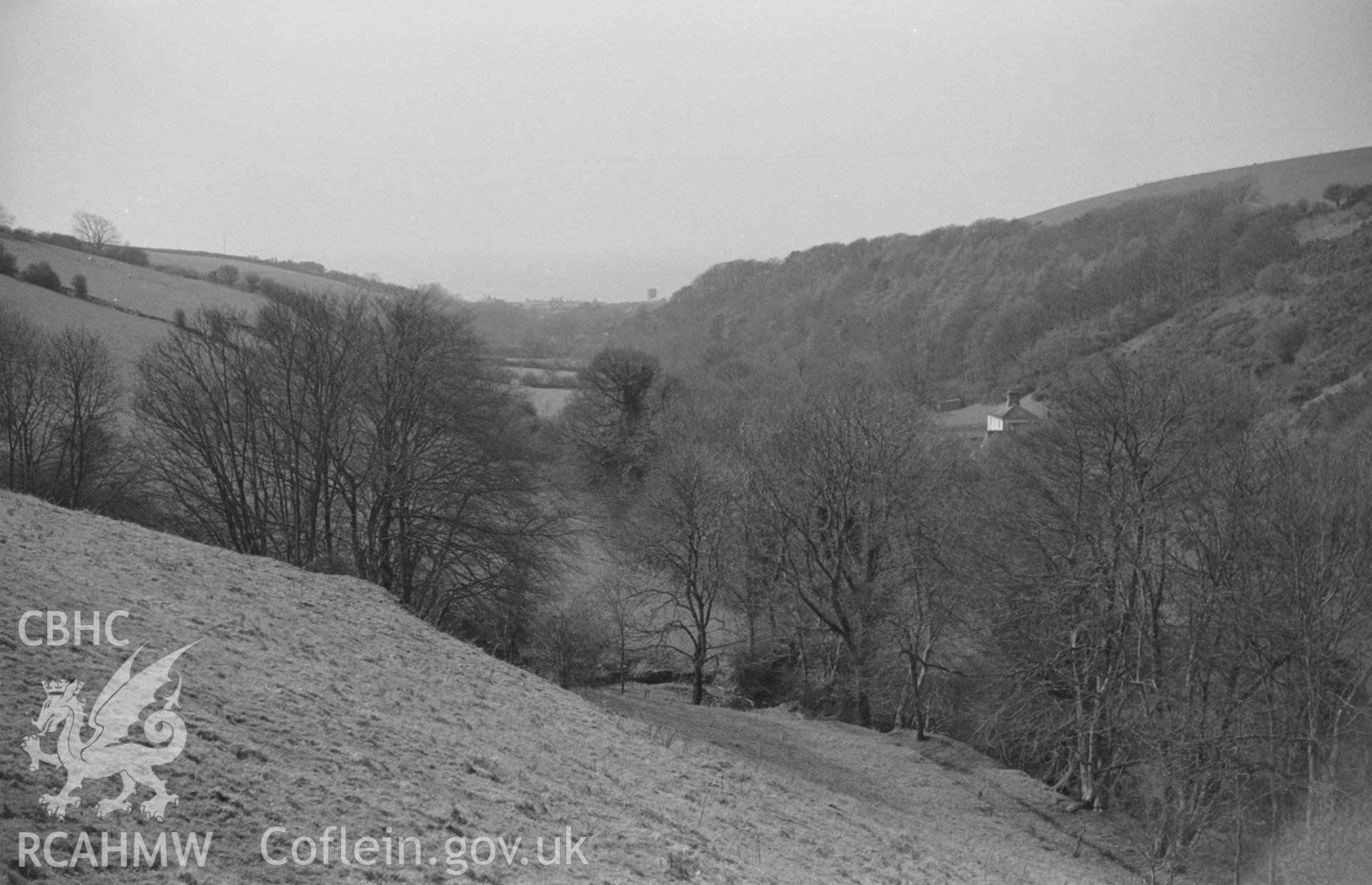 Black & White photograph showing view down the valley from track to Cwm-bach, 500m west south west of Felin Fach, with Cwm house on the right. Llansantffraid church in distance. Photograph by Arthur Chater, April 1962 from Grid Ref SN529669, looking west.