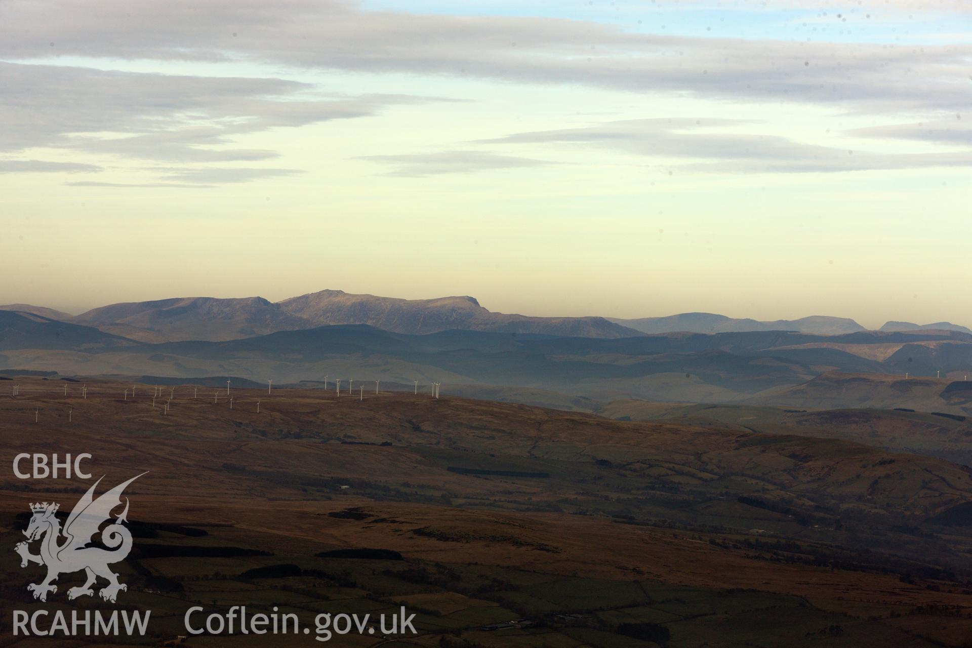 View of Carno Wind Farm, with Cadair Idris in the distance beyond. Oblique aerial photograph taken during the Royal Commission?s programme of archaeological aerial reconnaissance by Toby Driver on 28th February 2013.