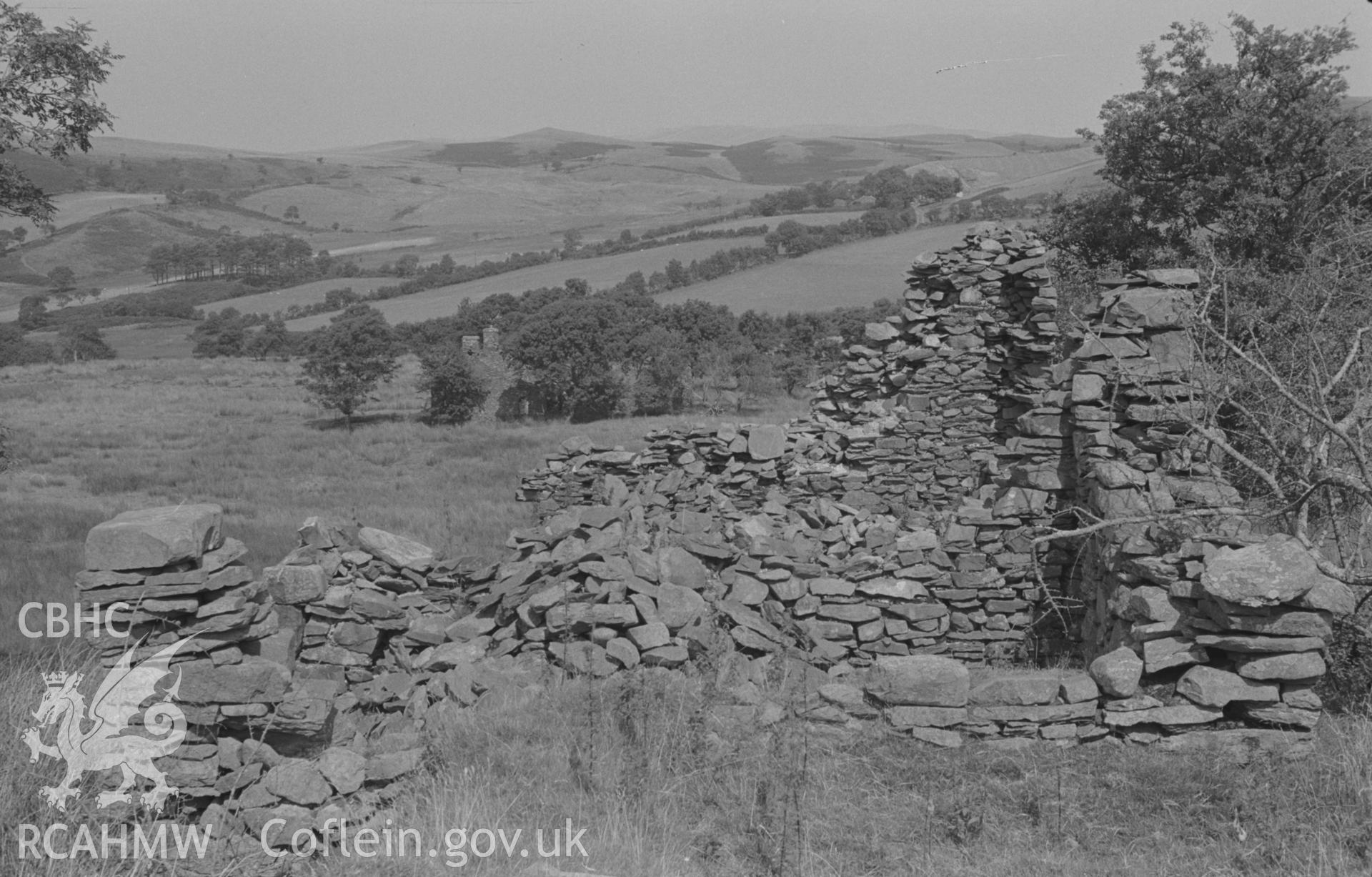 Digital copy of a black and white negative showing part of ruin of Ty Canol, halfway between Pen-Cwm and Ty-Newydd, at 1,000 ft. Pen-Cwm ruin beyond on left; Bryn-Eithiniog in distance on right. Part of the Bryneithinog squatter settlement. Photographed by Arthur O. Chater in August 1967. (Looking north from SN 7342 6320).