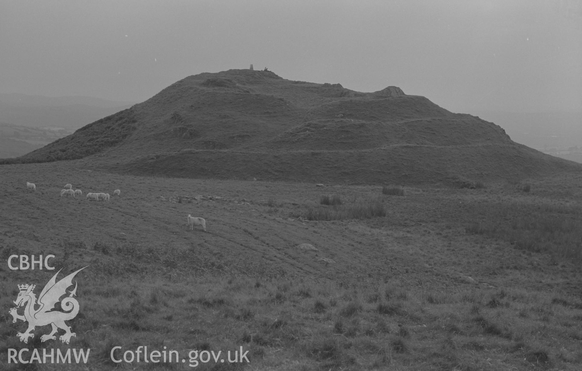 Digital copy of a black and white negative showing Pen y Bannau iron age camp, showing the entrance through the triple rampart at the north end. Photographed by Arthur O. Chater on 25th August 1967, looking south west from Grid Reference SN 743 670.