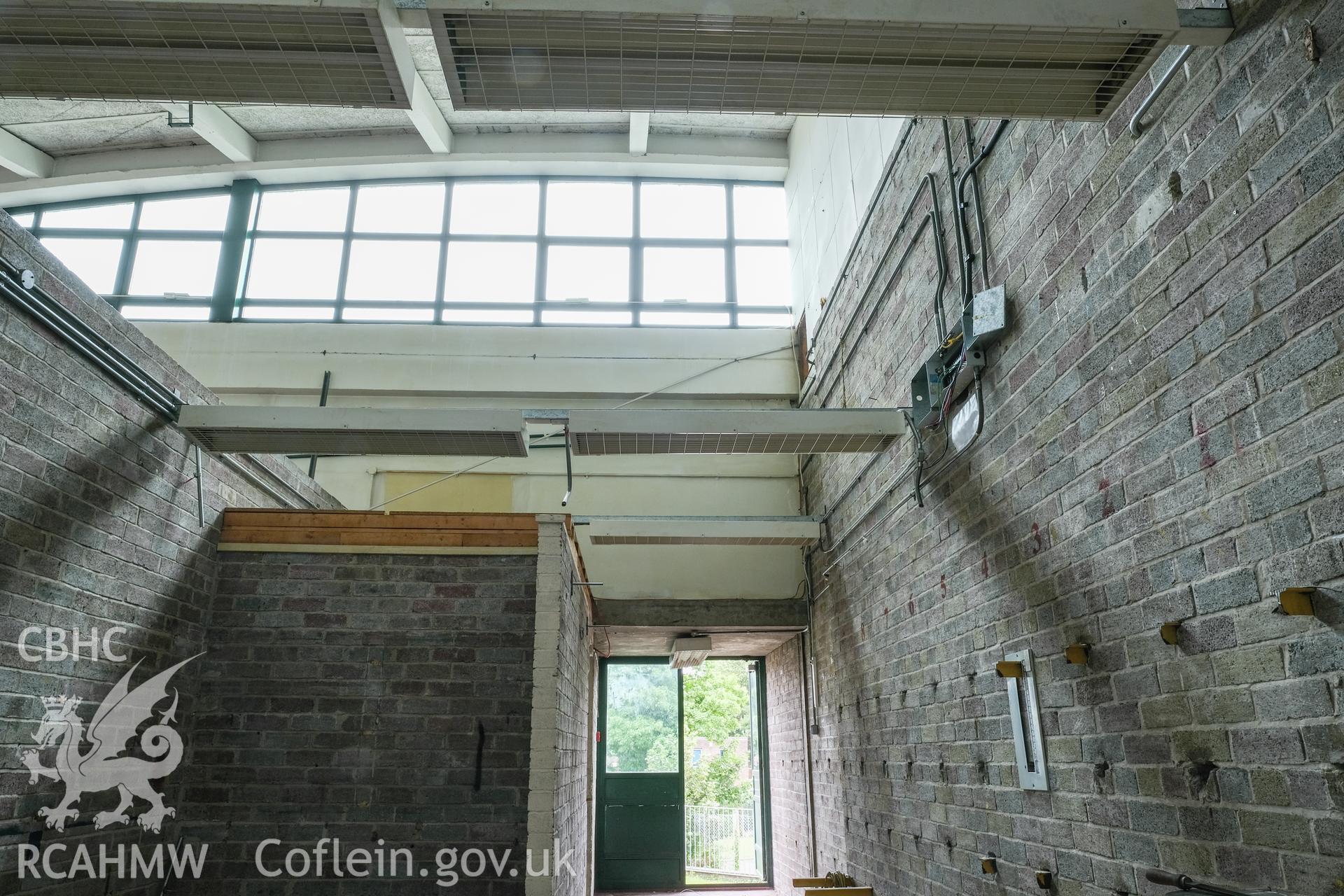 Digital colour photograph showing interior view of corridor, windows and entrance at Caernarfonshire Technical College, Ffriddoedd Road, Bangor. Photographed by Dilys Morgan, donated by Wyn Thomas of Grwp Llandrillo-Menai Further Education College, 2019.